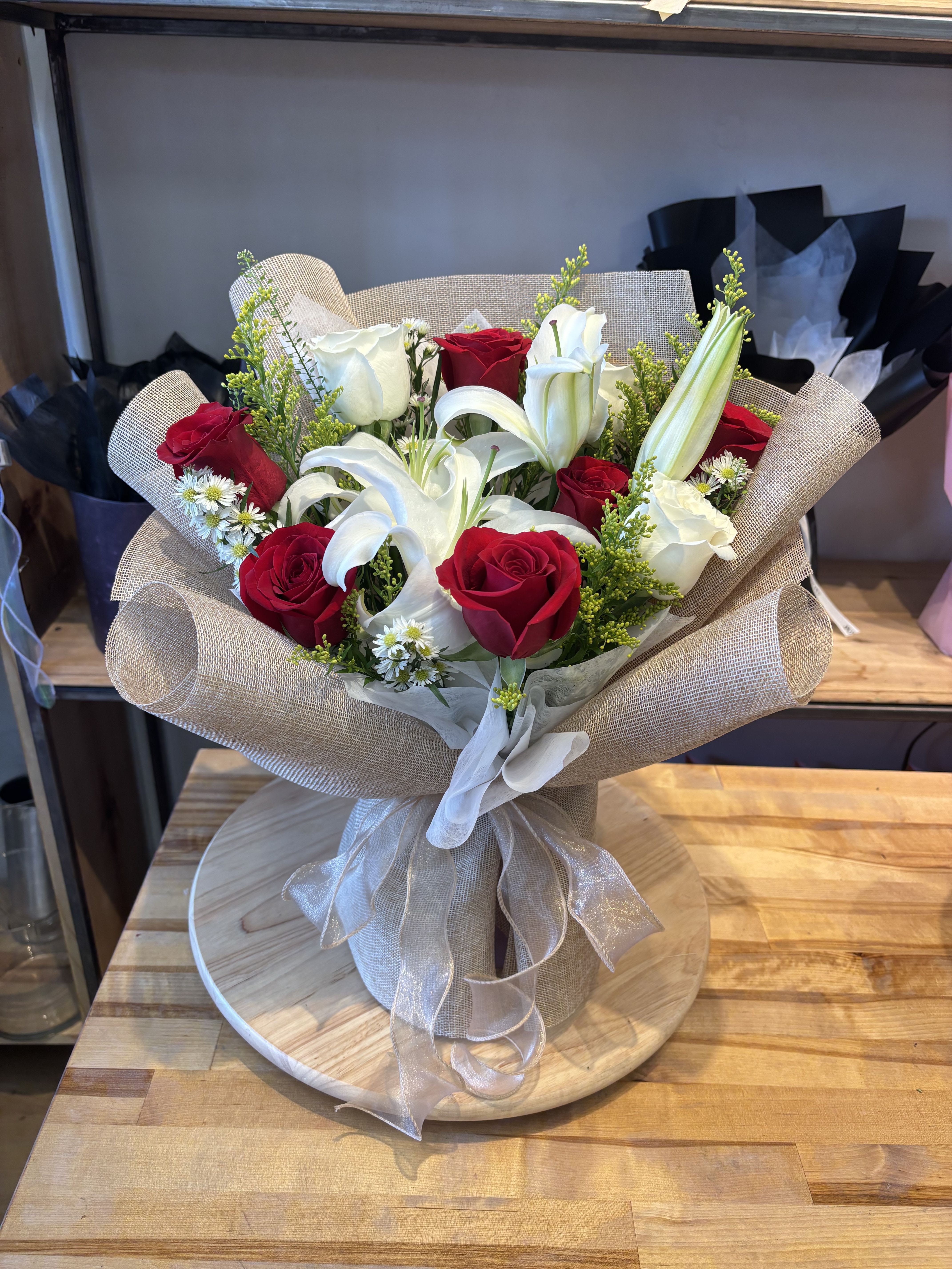Bouquet of red roses and white lilies wrapped in beige paper