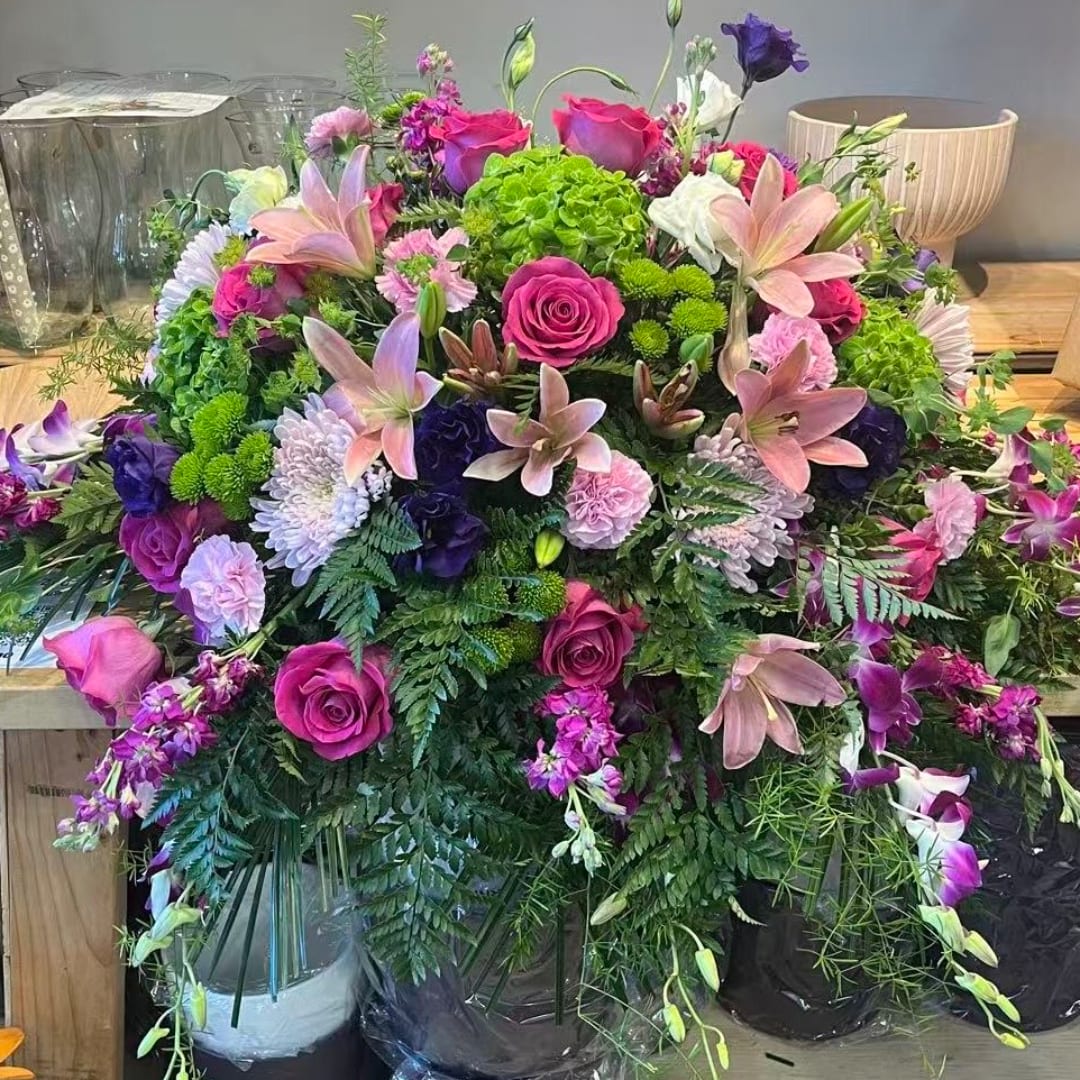 Large mixed bouquet with pink roses, lilies, and purple flowers in containers