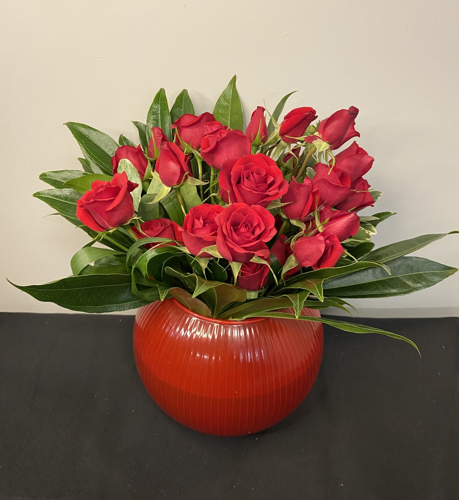 Love Note by Chasing Petals - Love Note is a refined expression of romance, featuring velvety red roses artfully arranged with lush, glossy greenery. Elegant and timeless, this design feels indulgent yet effortless—perfect for anniversaries, meaningful moments, or an elevated just because. A classic gesture, beautifully done.