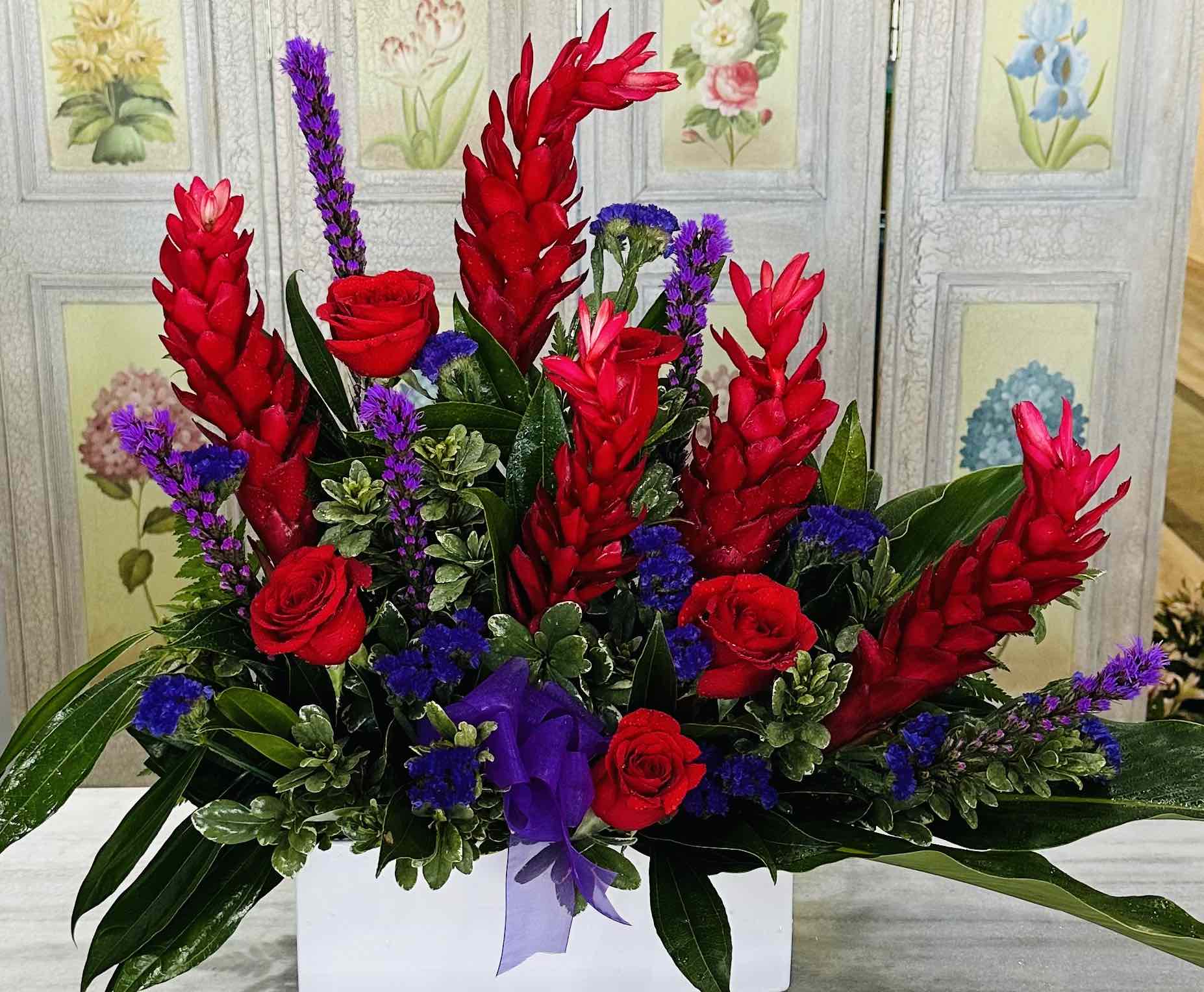 Burning Desire - The “Burning Desire” arrangement is an intense expression of emotion, a fiery bouquet that captures the heat of passion. At its heart, the commanding presence of red torch ginger stands tall, its vivid blooms like flames reaching skyward. These exotic flowers, bold and striking, are complemented by the regal purple liatris, whose slender spires add a touch of wild sophistication.  