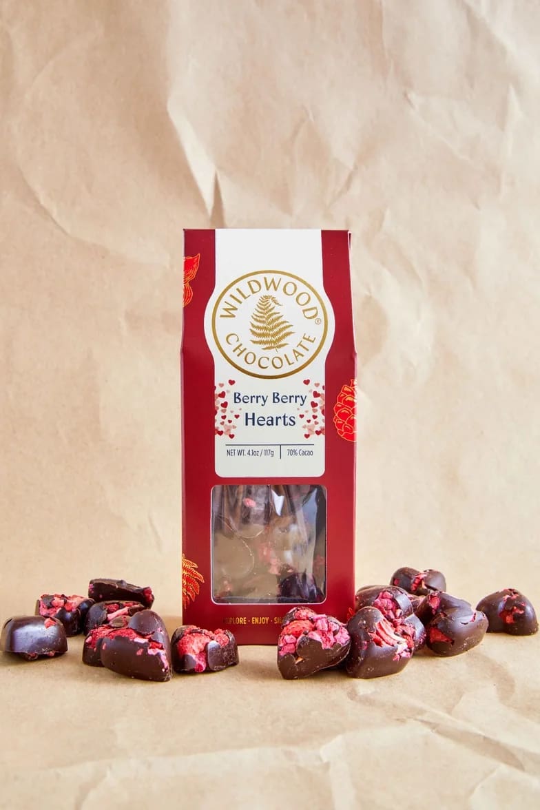 Box of berry chocolate hearts with pieces scattered around it