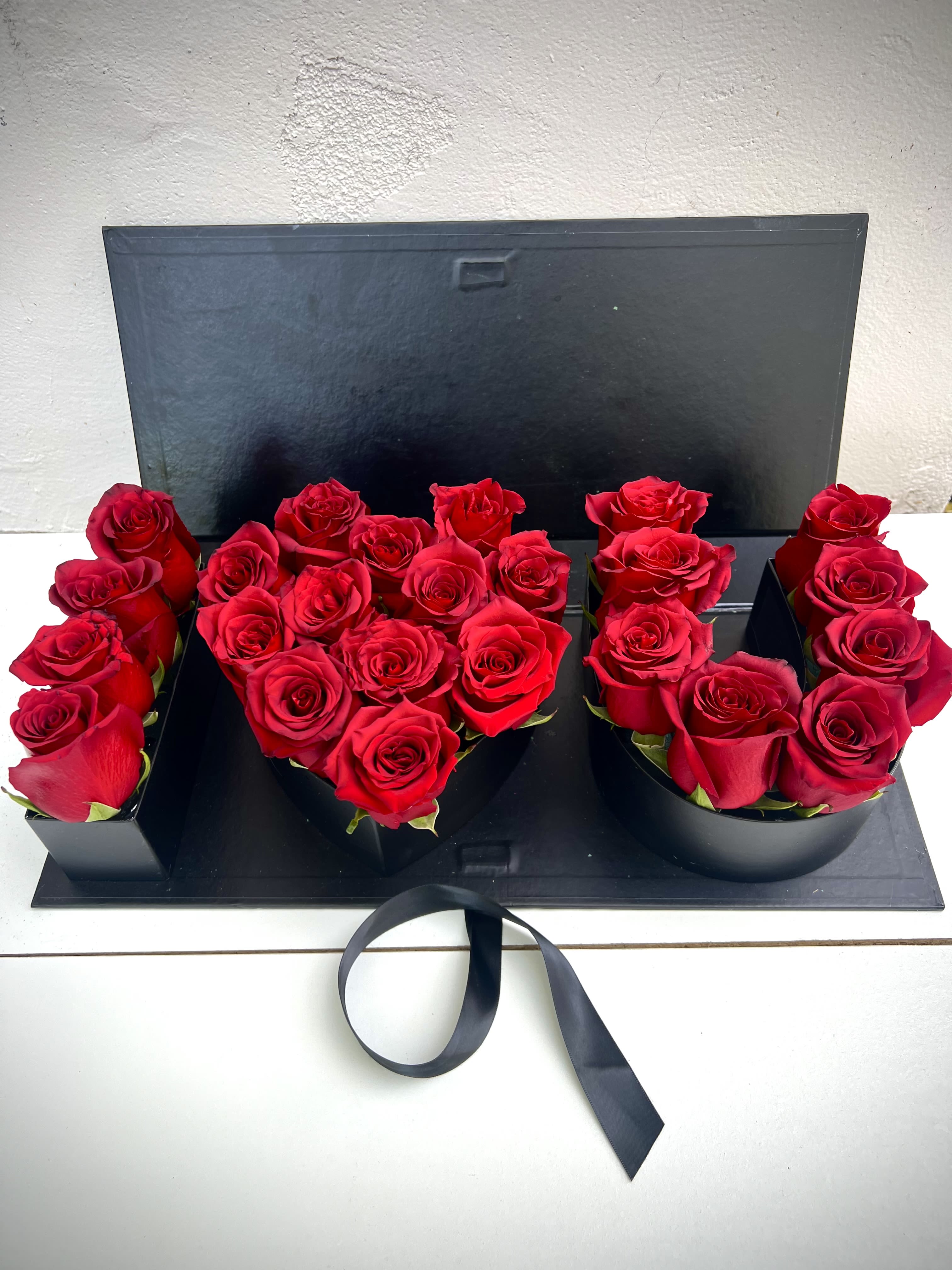 Red roses arranged in a black presentation box with a ribbon