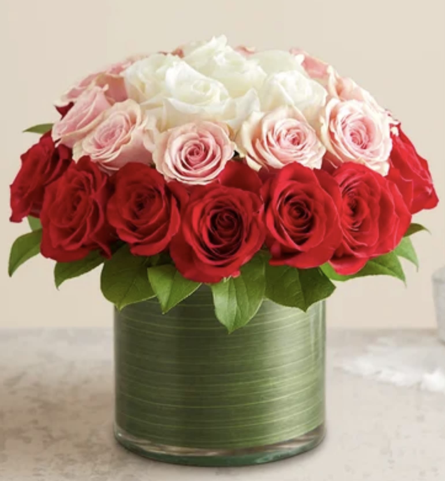 Red, pink, and white roses arranged in a green vase