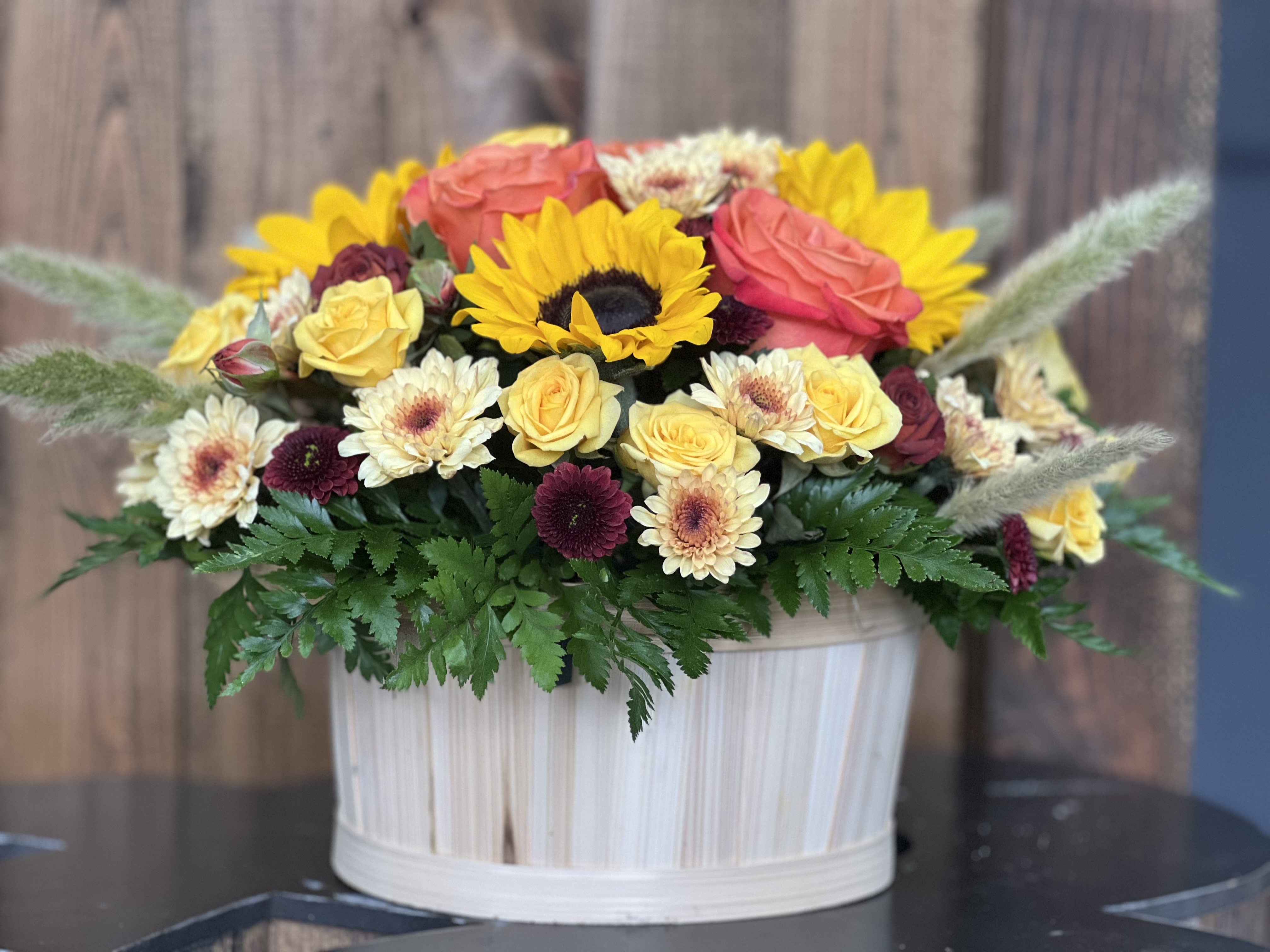 Mixed bouquet in a white ribbed container with sunflowers and roses