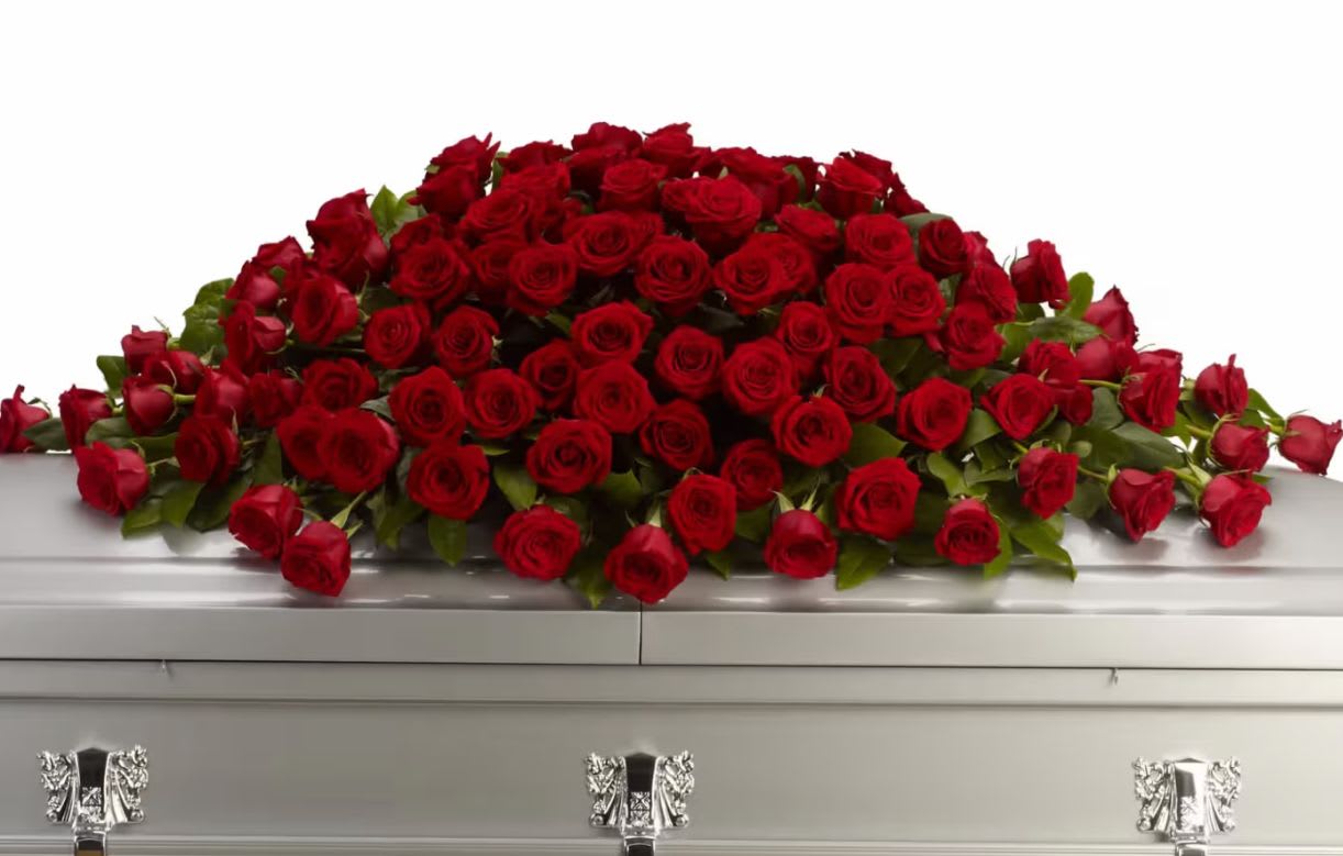 Large spray of red roses on a white casket