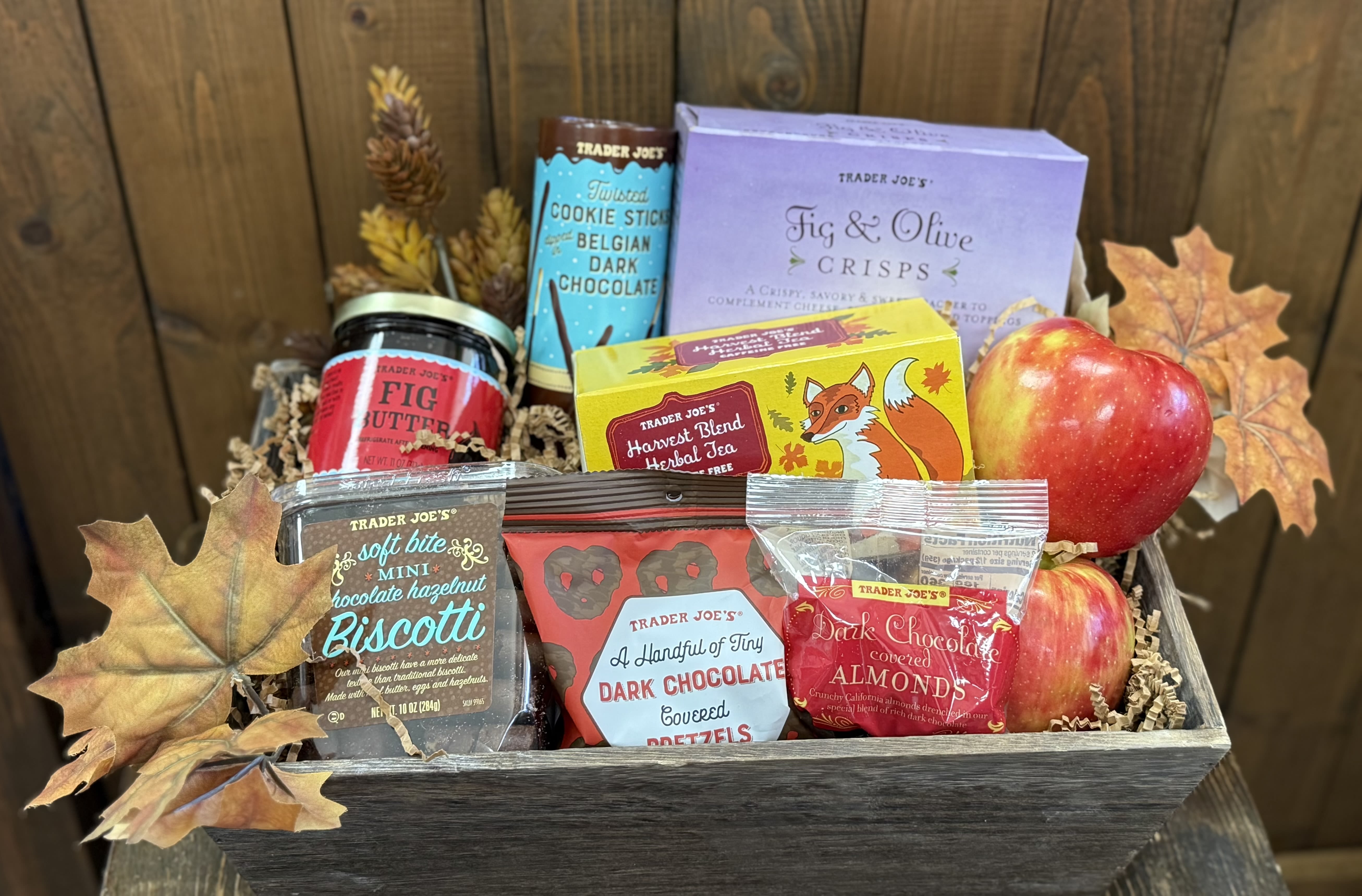 Gift basket with apples, snacks, tea, and autumn leaves