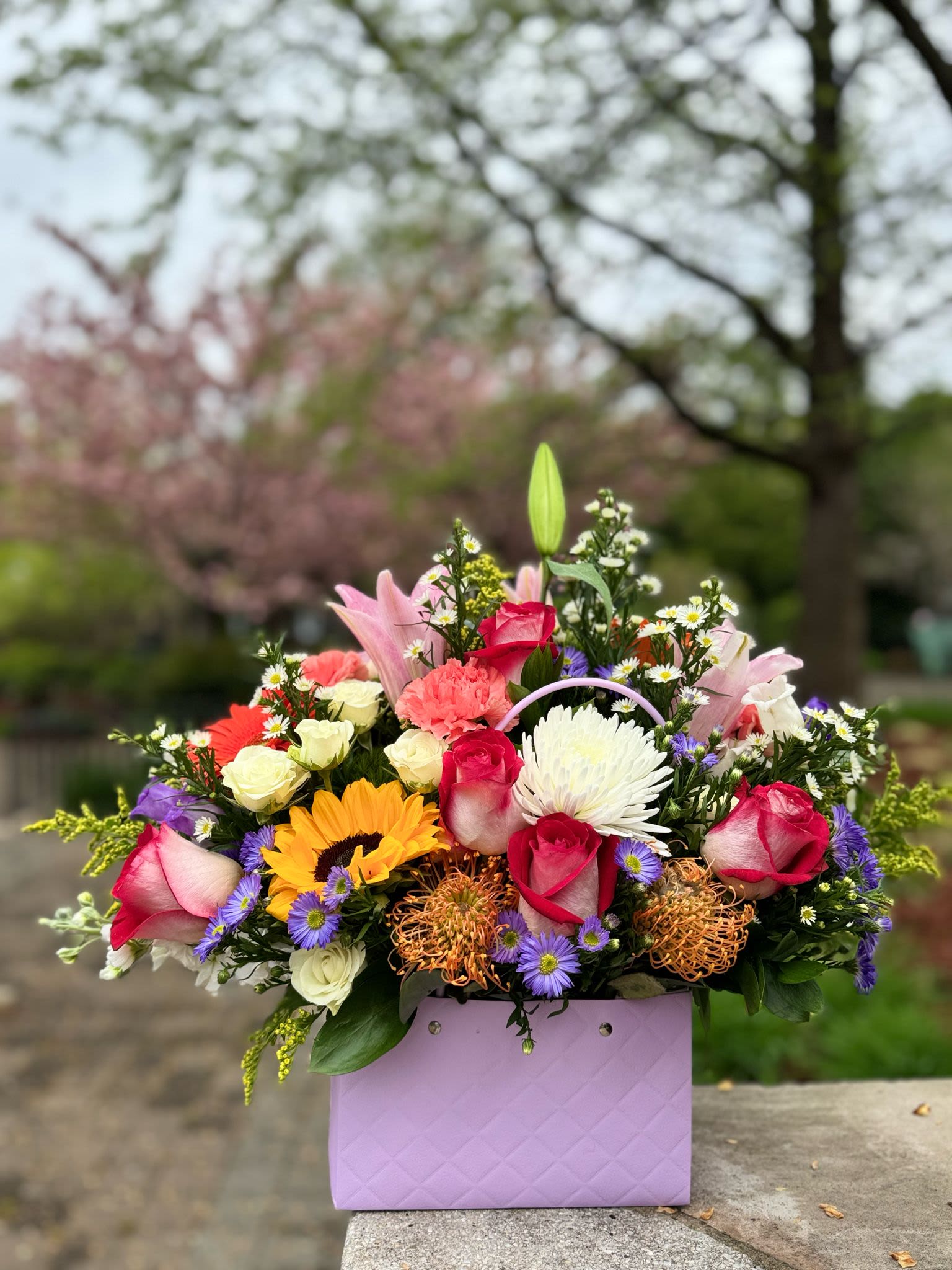 Mom's Sweetness - A charming floral bag filled with gerberas delicate roses, and a bright sunflower.