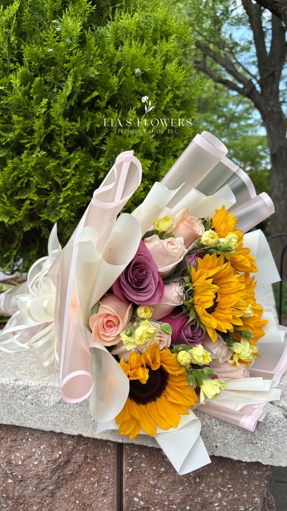 Bouquet of roses and sunflowers wrapped in pale pink and white paper