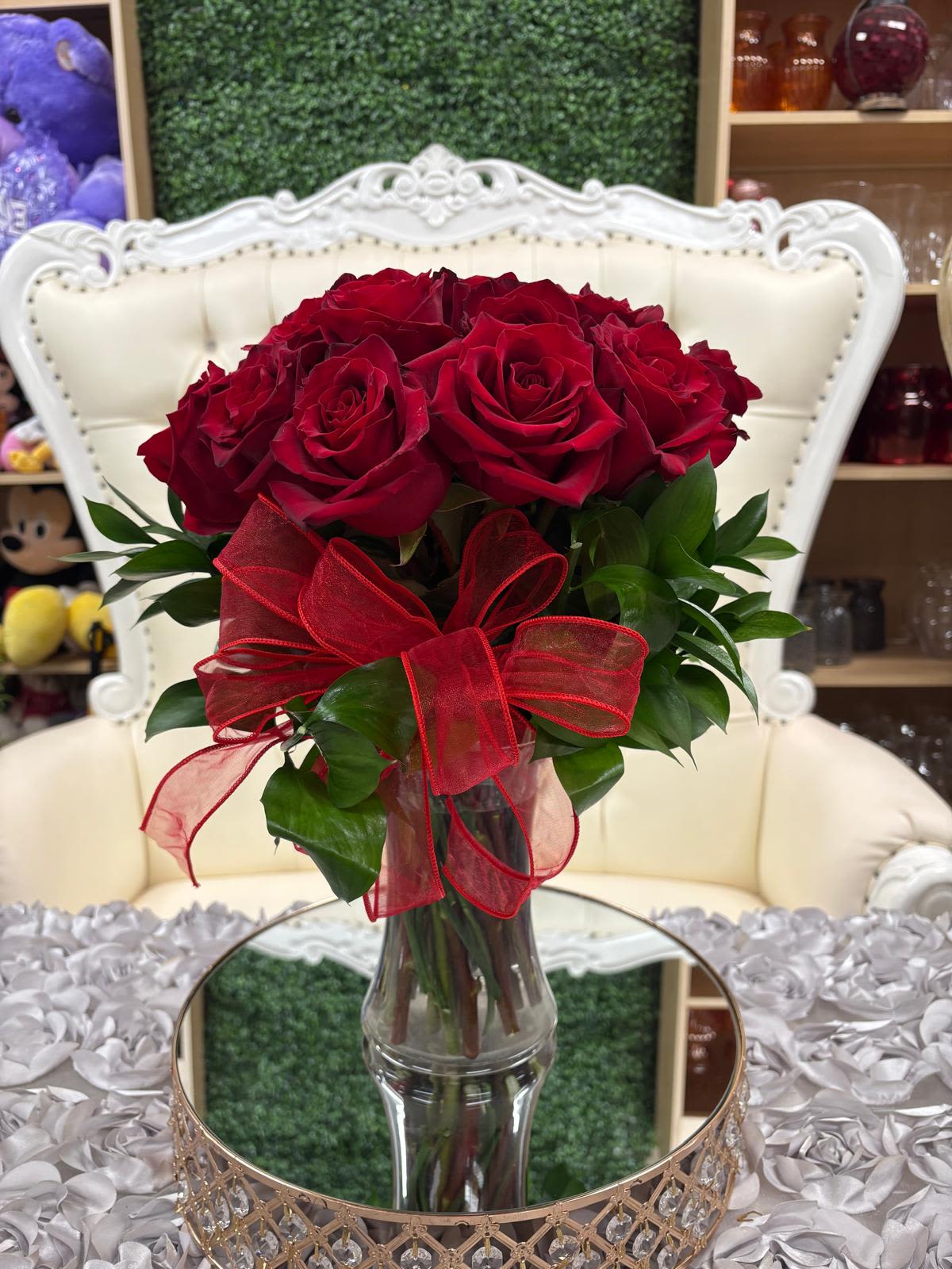 Bouquet of red roses in a clear glass vase with a red ribbon