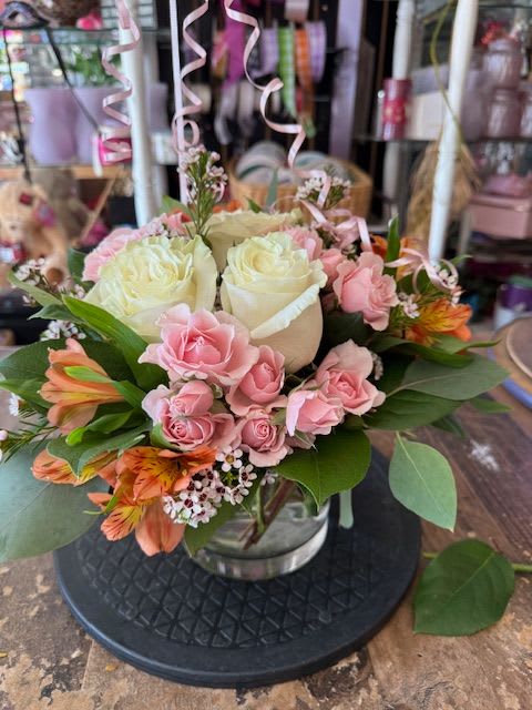 Pink and white rose bouquet in a glass vase with orange flowers