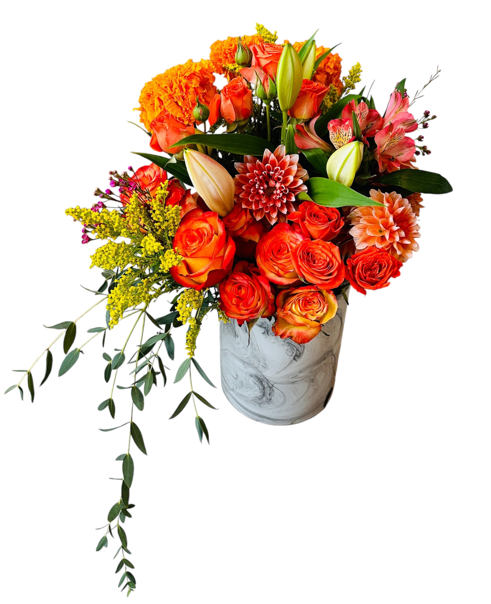 Asymmetrical orange and yellow flower arrangement with roses, lilies, and dahlias in a marbled white vase