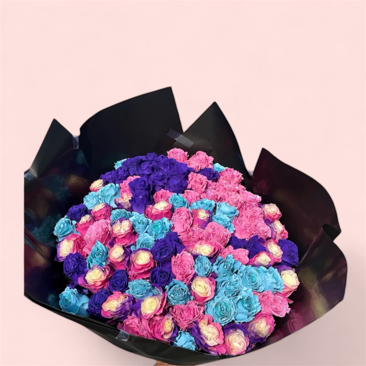 Large bouquet of pink, purple, and blue roses wrapped in black paper