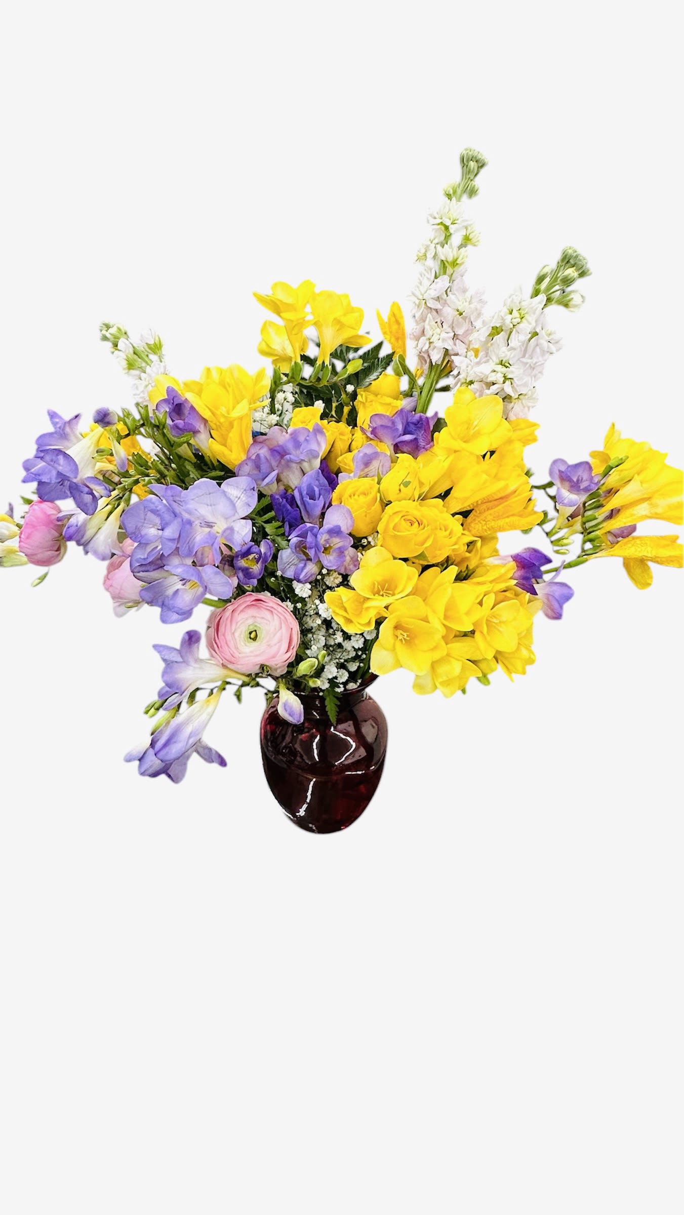 Bright yellow and lavender freesias with pink blooms arranged in a dark red glass vase