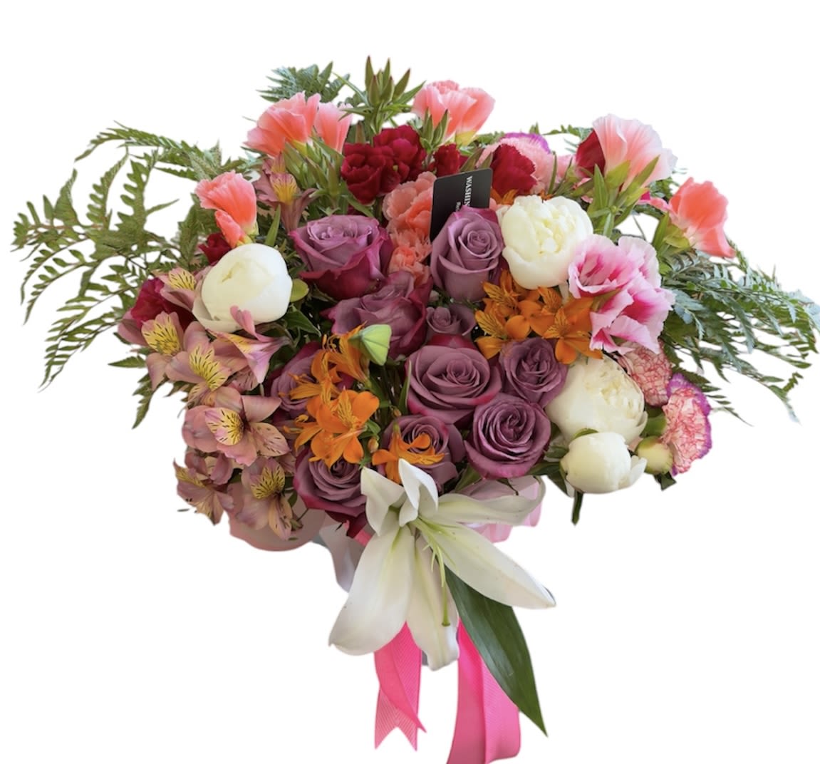 Mix Designer choice Arrangement  - A lush, hand-tied bouquet that reads like a celebration in color-soft pink and lavender roses crown the center while white lilies and alstroemeria punctuate the mix with clean contrast, and pops of orange carnations add unexpected warmth. Perfect as a birthday bouquet, anniversary gift, or a romantic surprise, this arrangement is designed to make the person you're thinking of feel cherished and joyfully noticed.  Dense and rounded in form, the arrangement is finished with fern-like greenery that frames the blooms and a bright pink ribbon that heightens the celebratory, romantic tone. Each stem is bouquet-wrapped and includes a floral tag for your message; the layered textures-from velvety roses to trumpet lilies and delicate alstroemeria-create visual depth and a fragrant, inviting presence on arrival. 