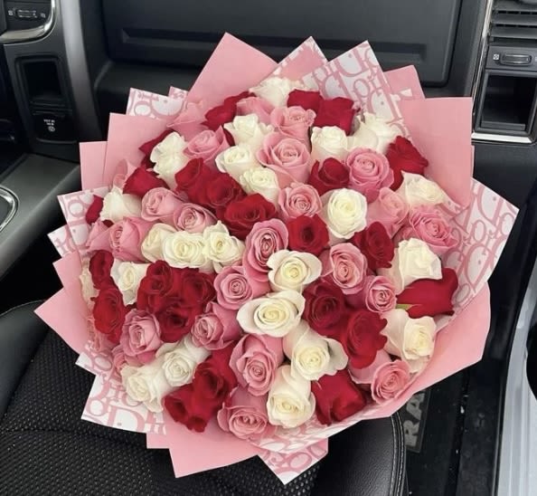 Large bouquet of pink, red, and white roses wrapped in pink paper