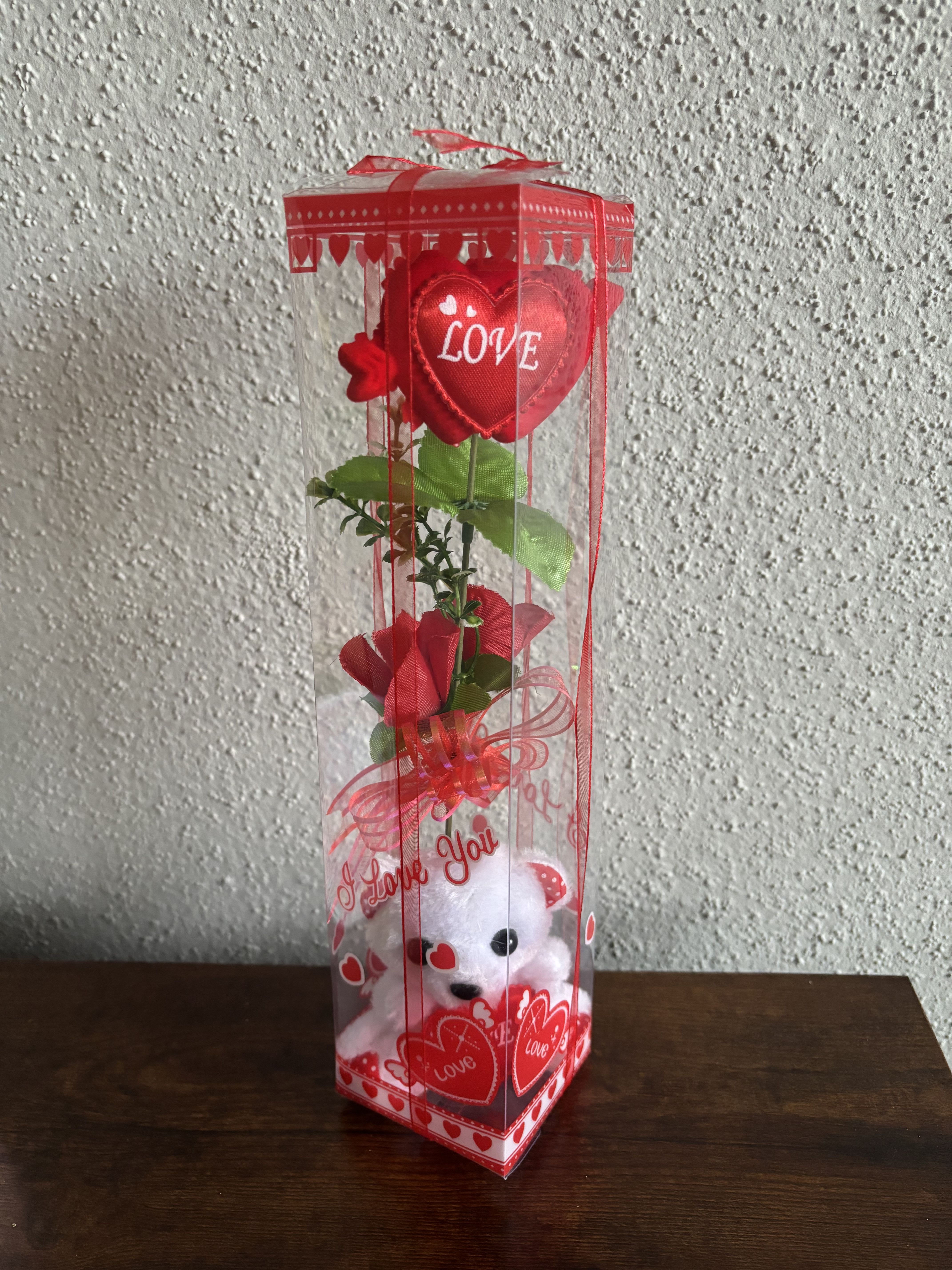 Red heart-themed gift box with a teddy bear and artificial rose stem