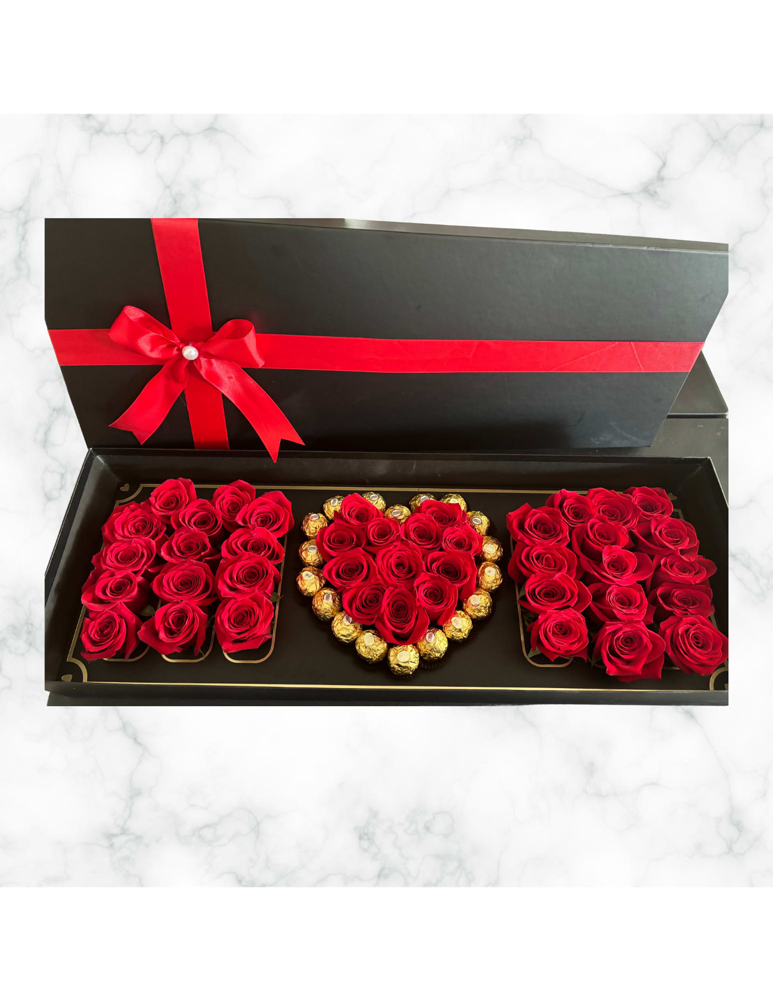 Black gift box with red roses and chocolates arranged in heart shapes