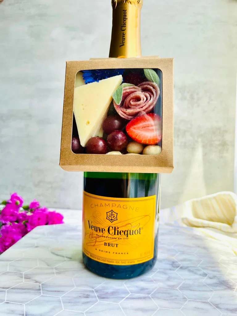 Champagne bottle with a fruit-and-cheese gift box attached