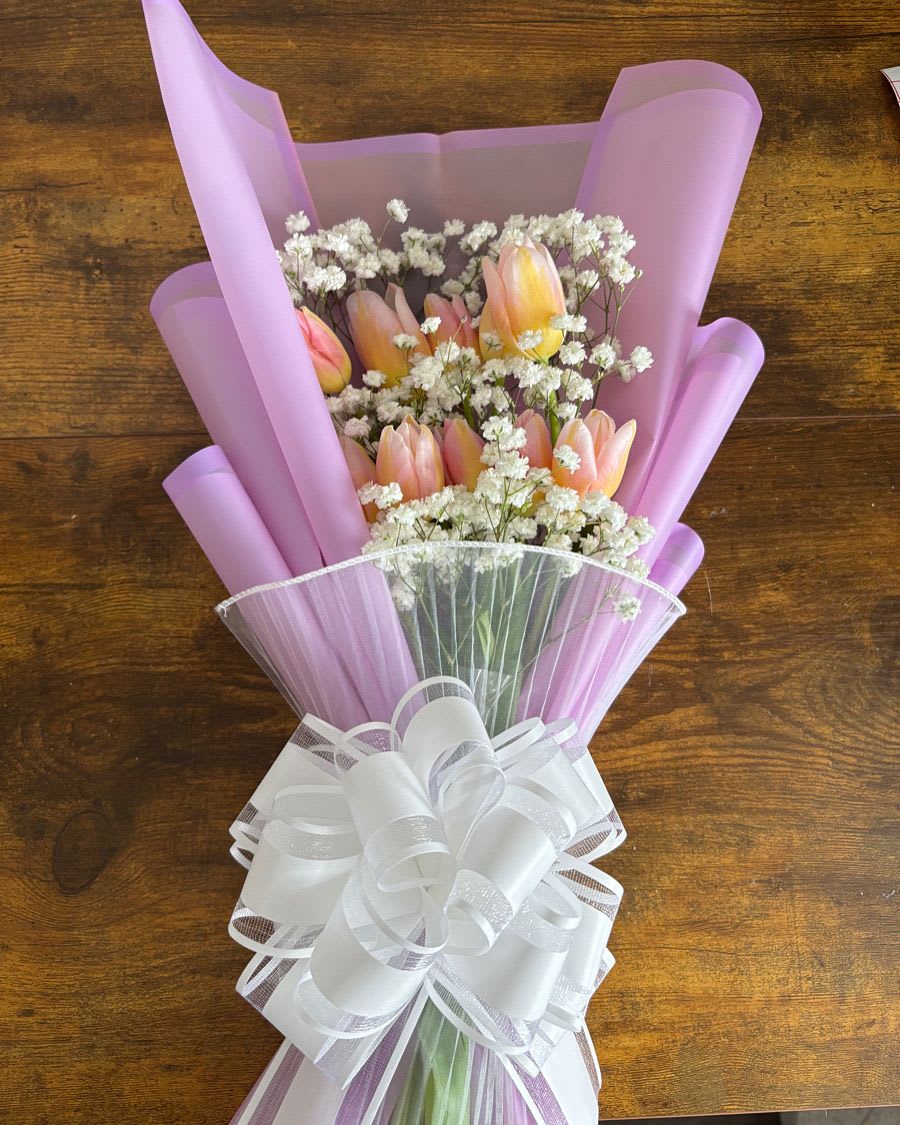 Pink tulip bouquet with white filler flowers and a large white bow