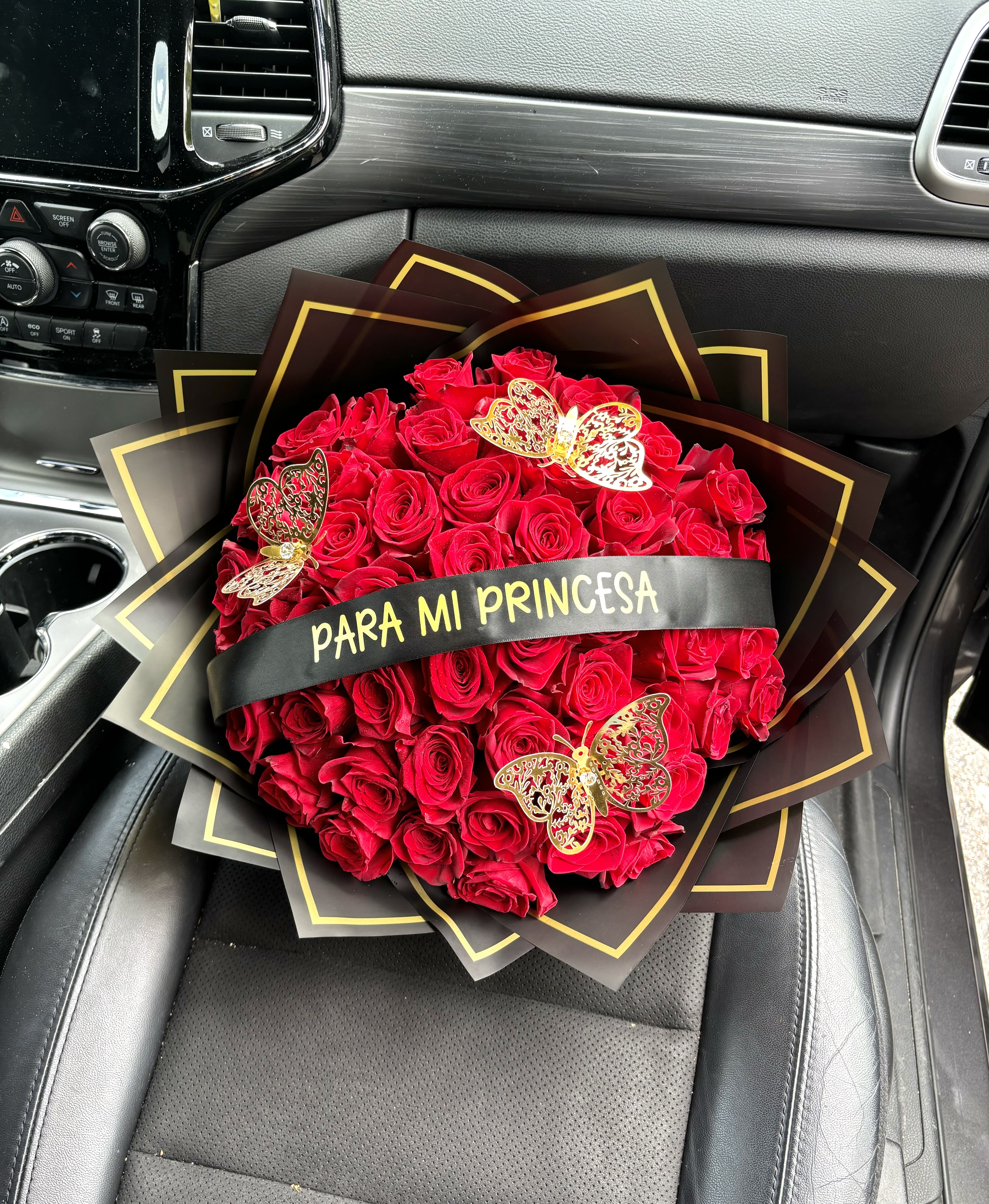 Bouquet of red roses with butterfly decorations and a ribbon reading "PARA MI PRINCESA"