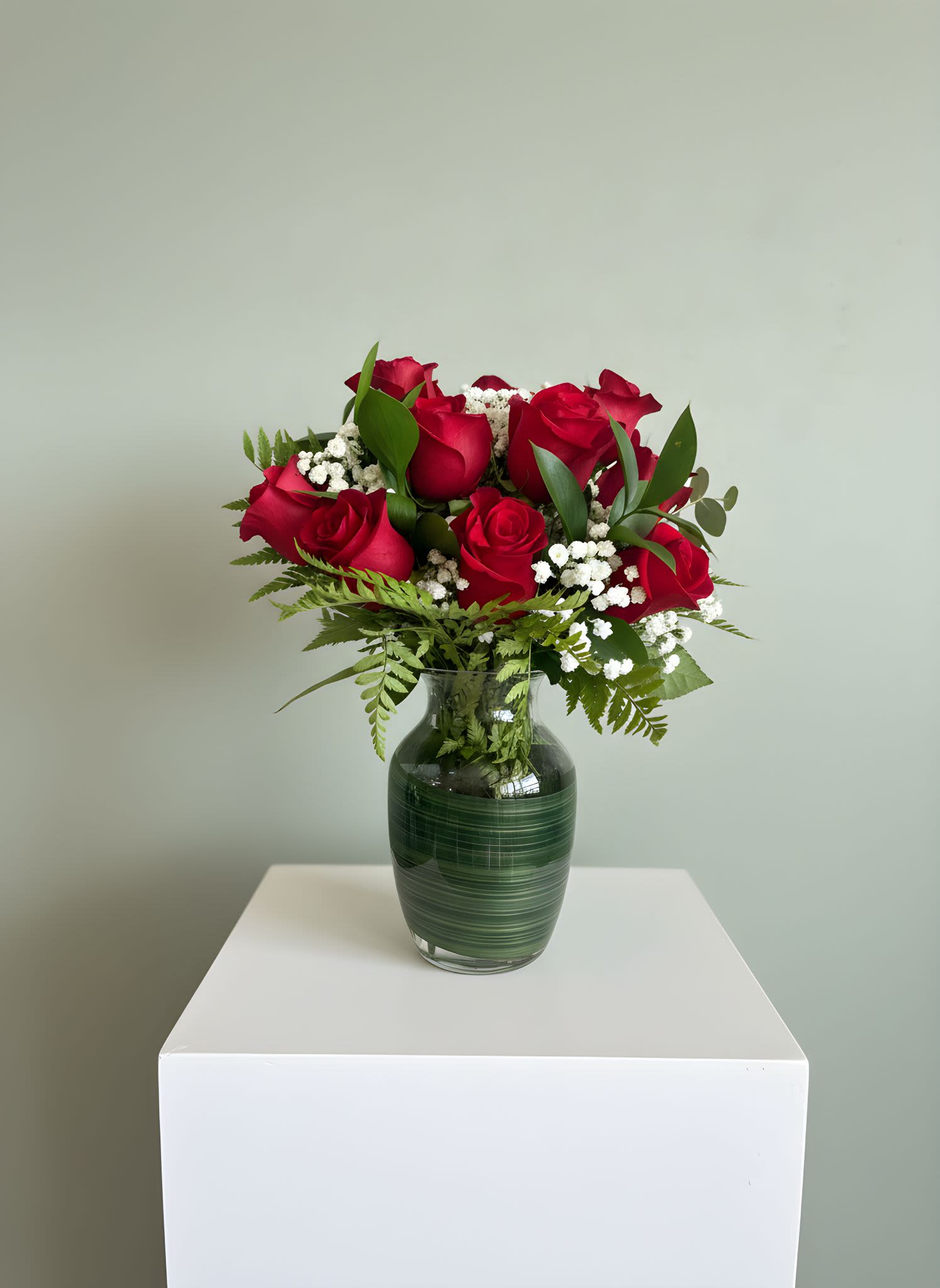 Classic 12 Red Rose Vase Arrangement  - Our Classic Red Rose Vase Arrangement is a timeless expression of love and elegance. This beautiful arrangement features fresh red roses accented with delicate baby’s breath and lush greenery, carefully arranged in a modern glass vase for a clean and romantic presentation.  Perfect for anniversaries, romantic surprises, birthdays, or simply letting someone know you care, red roses remain the ultimate symbol of love and admiration.  Each arrangement is handcrafted with care to ensure freshness, fullness, and a beautifully balanced design.  Please note: Rose bloom size and greenery may vary slightly depending on seasonal availability while maintaining the overall style and fullness of the arrangement.