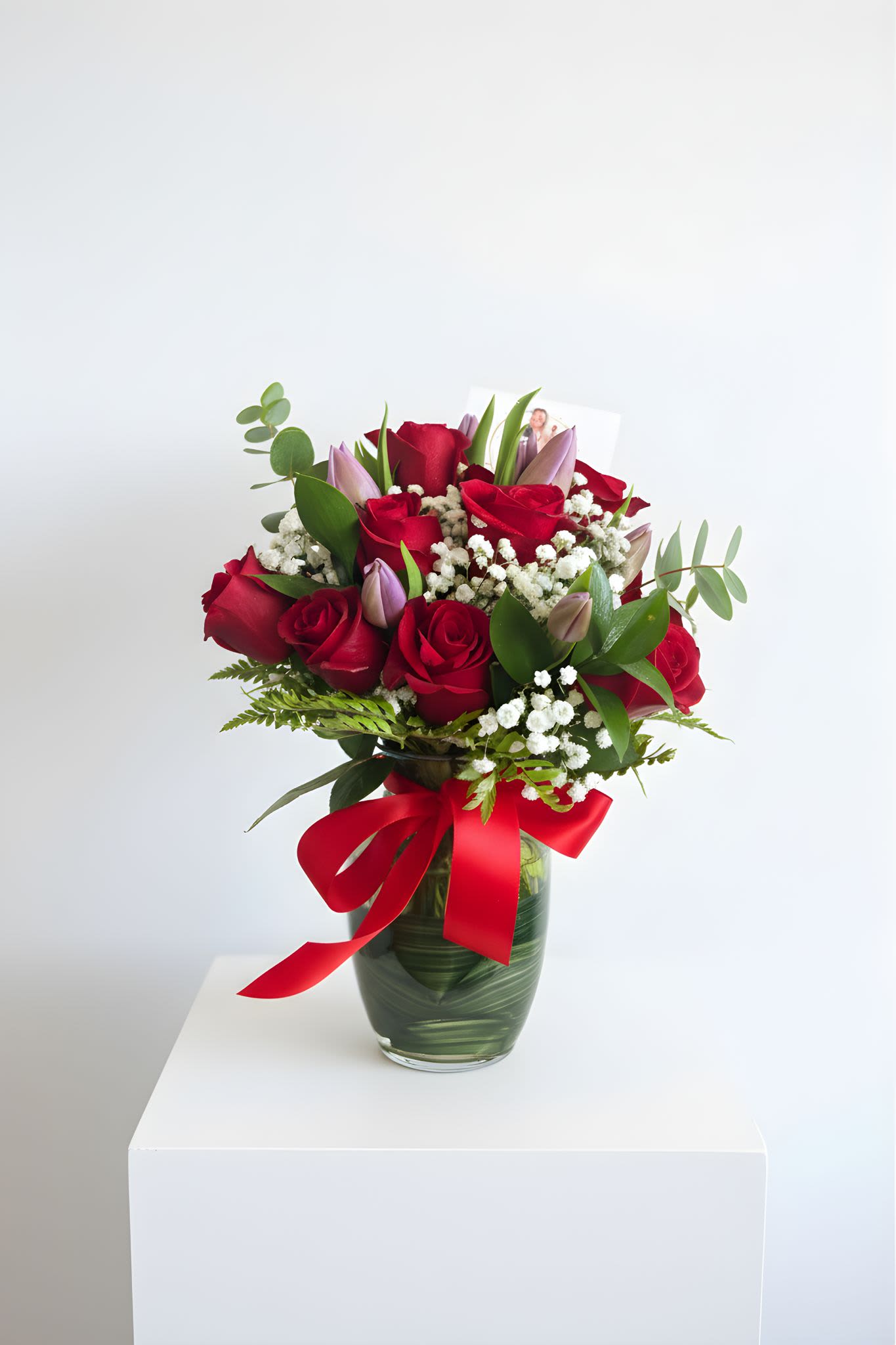 Romantic Garden Rose &amp; Tulip Arrangement - A beautiful expression of love and elegance, our Romantic Garden Rose &amp; Tulip Arrangement features a stunning mix of fresh red roses, delicate tulips, baby’s breath, and lush greenery arranged in a modern glass vase and finished with a romantic ribbon.  This arrangement blends classic romance with a soft garden-inspired style, making it perfect for anniversaries, birthdays, romantic surprises, or just because.  Each arrangement is handcrafted with care to create a full, balanced, and elegant design that brings warmth and beauty to any space.  Please note: Flower varieties and shades may vary slightly depending on seasonal availability. The photo represents the overall style and color palette of the arrangement.