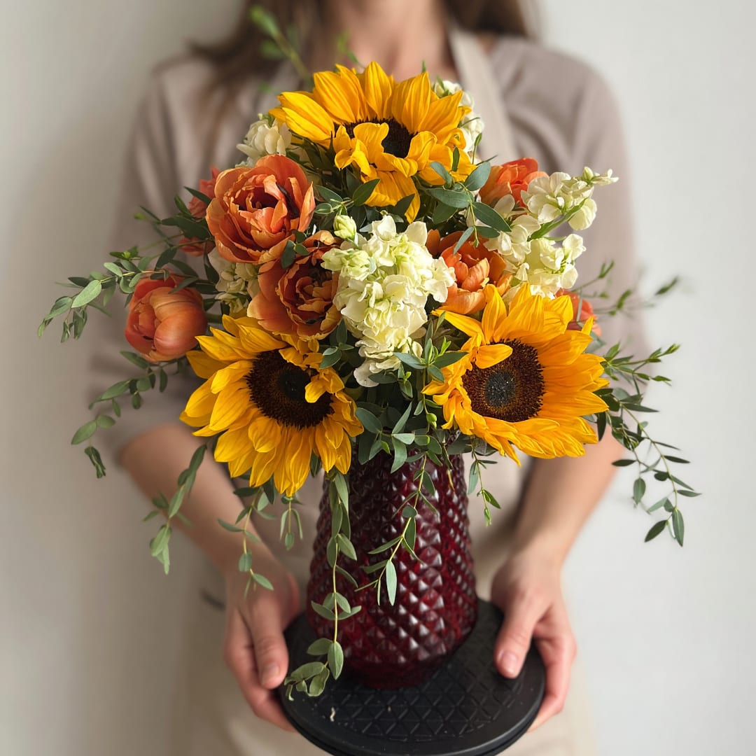 Bouquet of sunflowers, orange blooms, and white flowers in a red vase