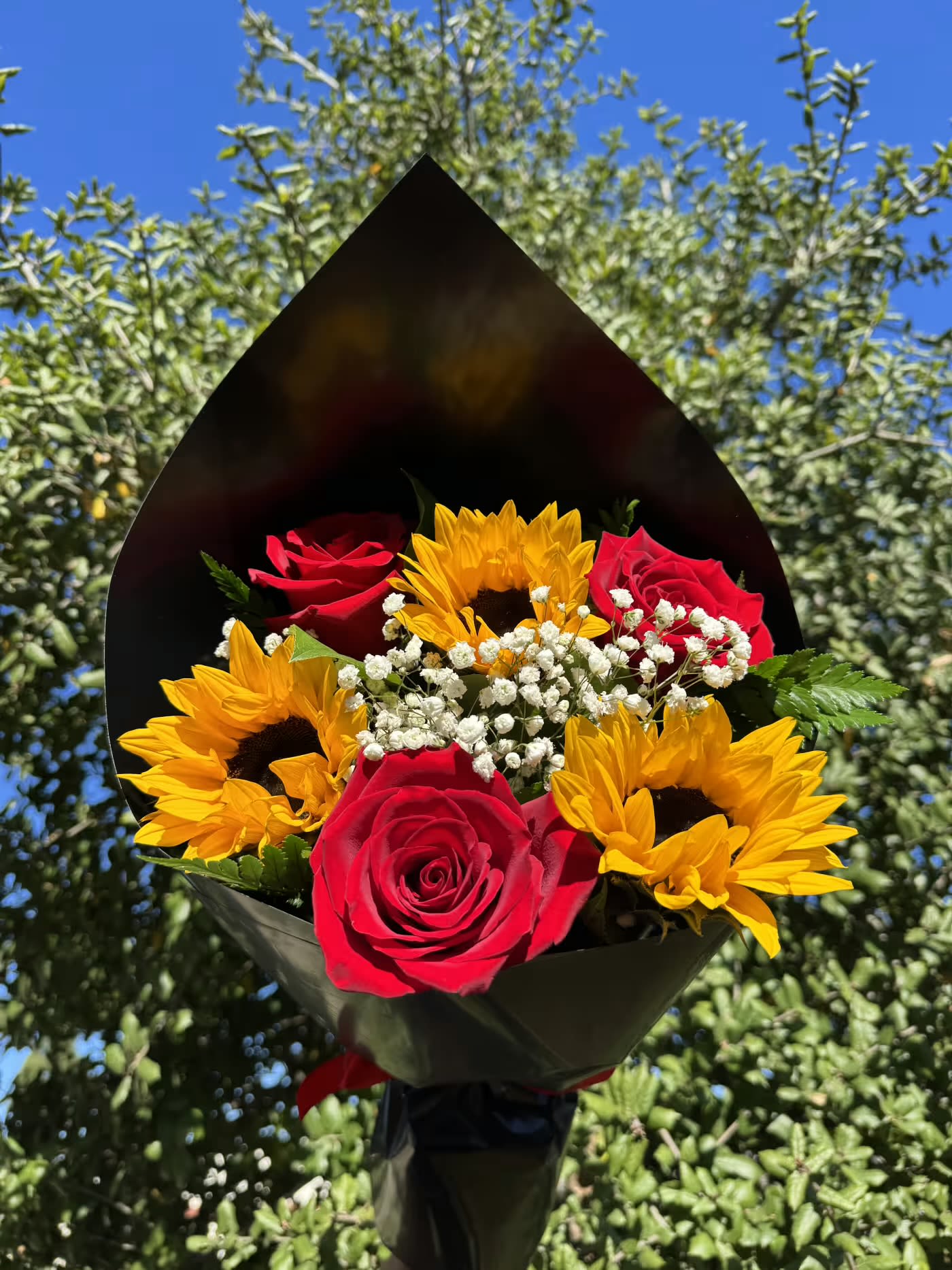 Bouquet of red roses and yellow sunflowers wrapped in black paper