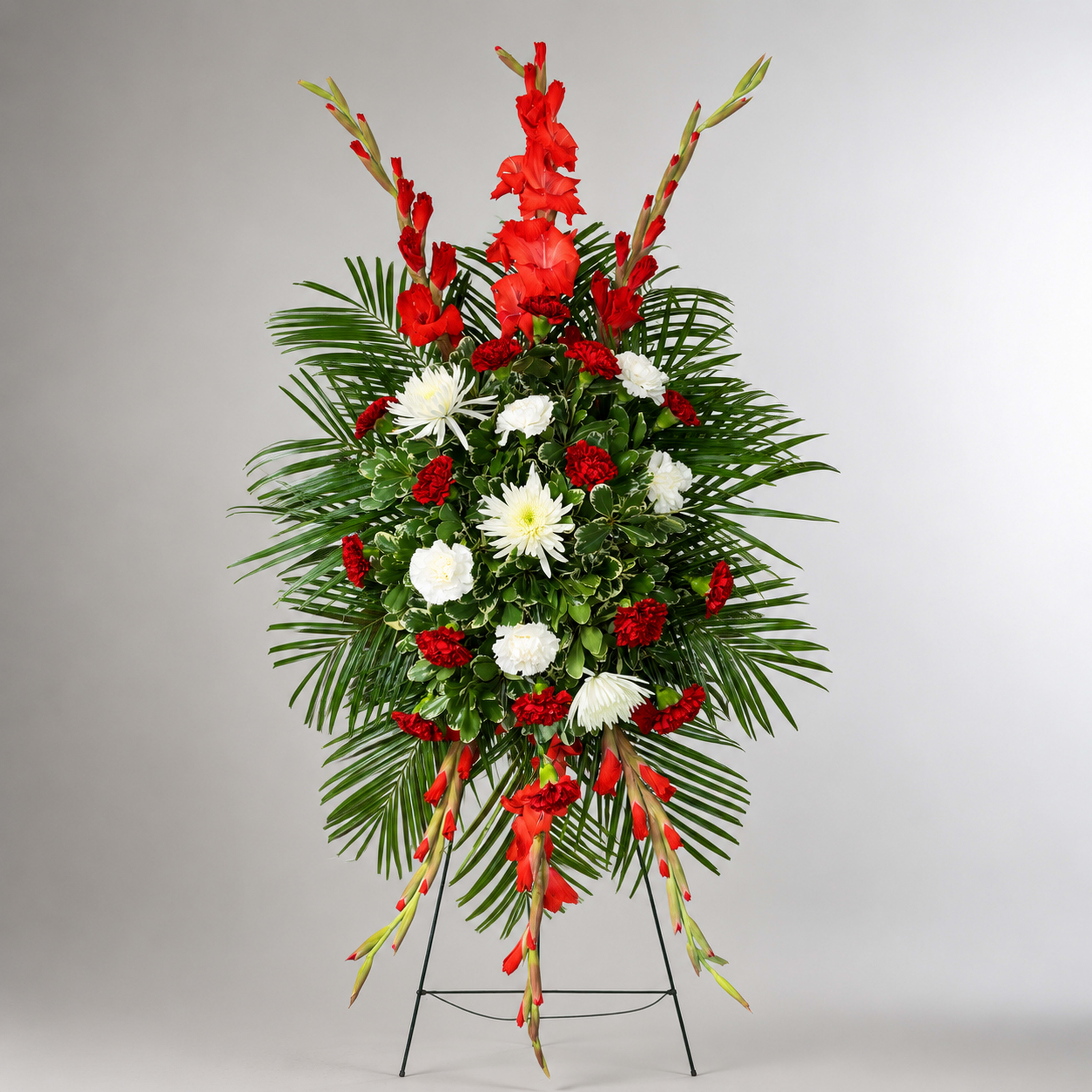 Standing floral spray with red and white flowers on a metal easel