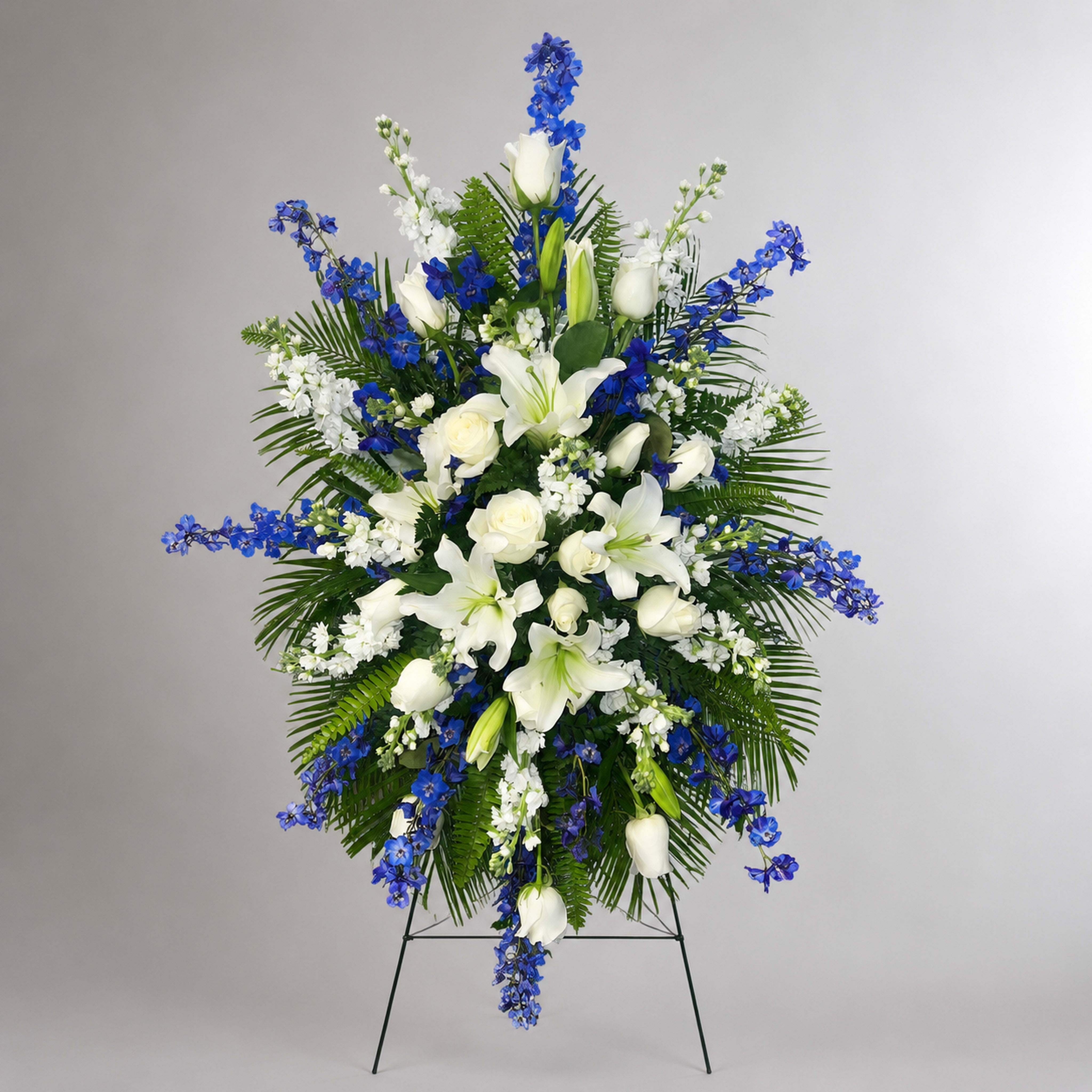 Standing floral spray with white lilies, roses, and blue flowers