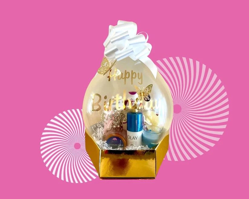 Birthday gift basket with a clear balloon topper and white bow