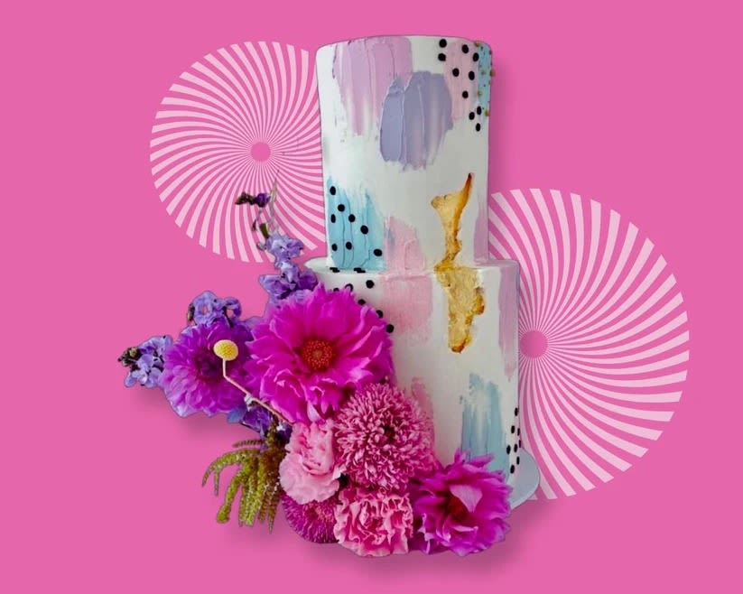 Pink floral arrangement beside a painted two-tier cake