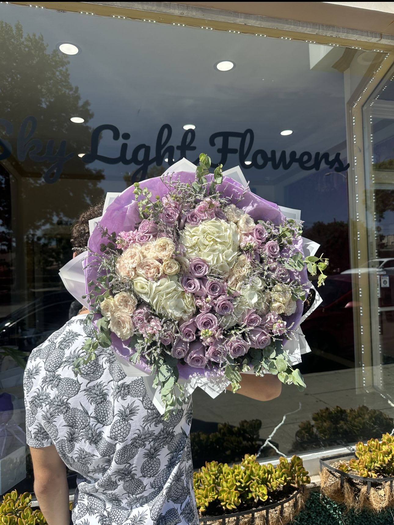 Large bouquet of lavender and cream roses wrapped in purple paper