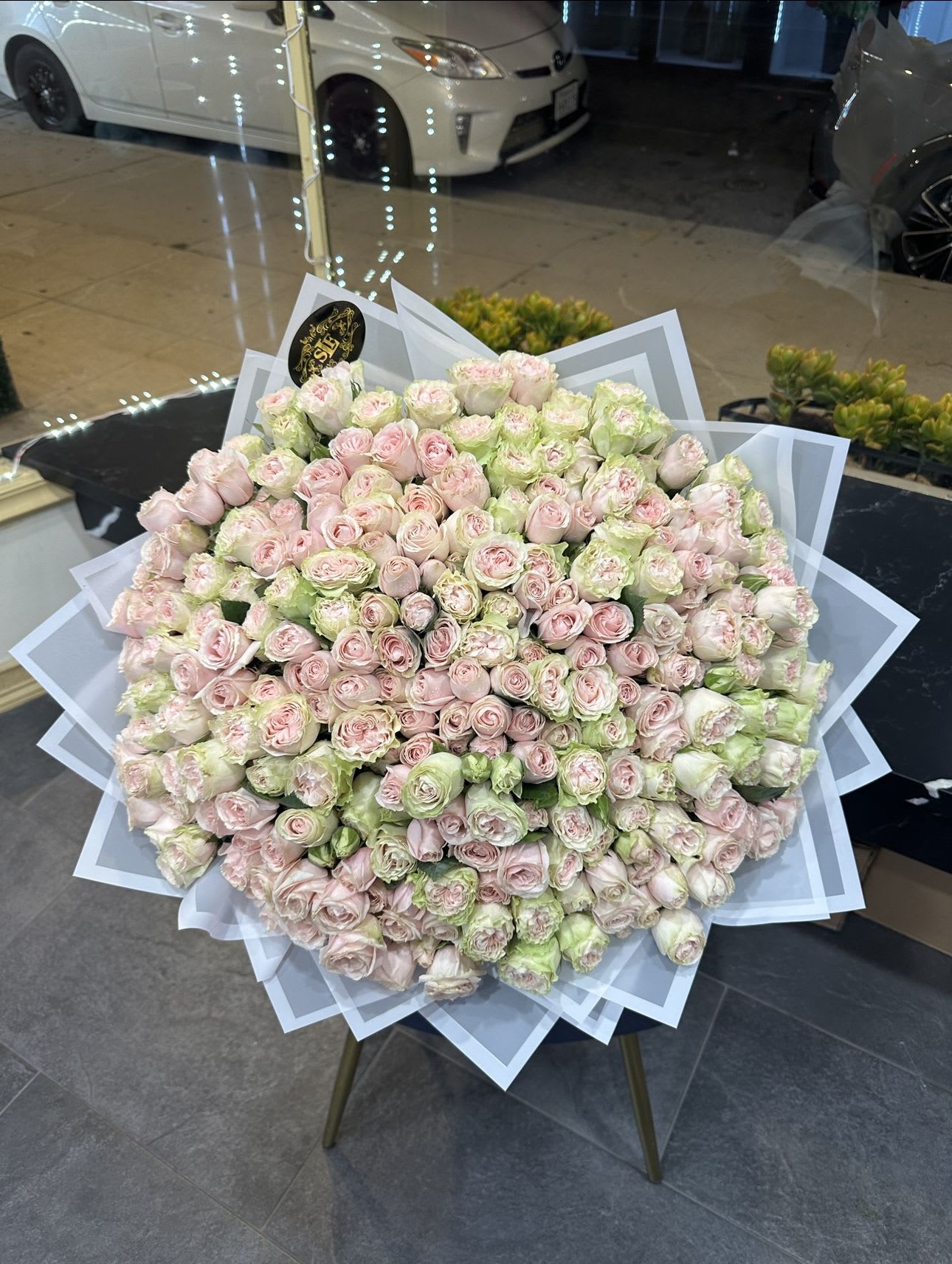 Large bouquet of pale pink and green roses wrapped in white paper