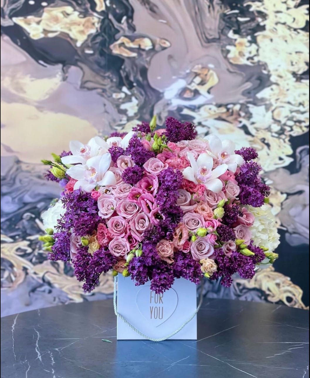 Pink and purple flower arrangement in a white gift box
