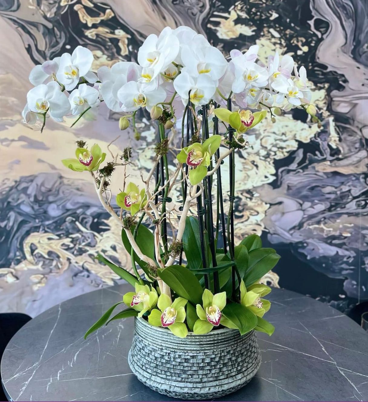 White and green orchids arranged in a textured round pot