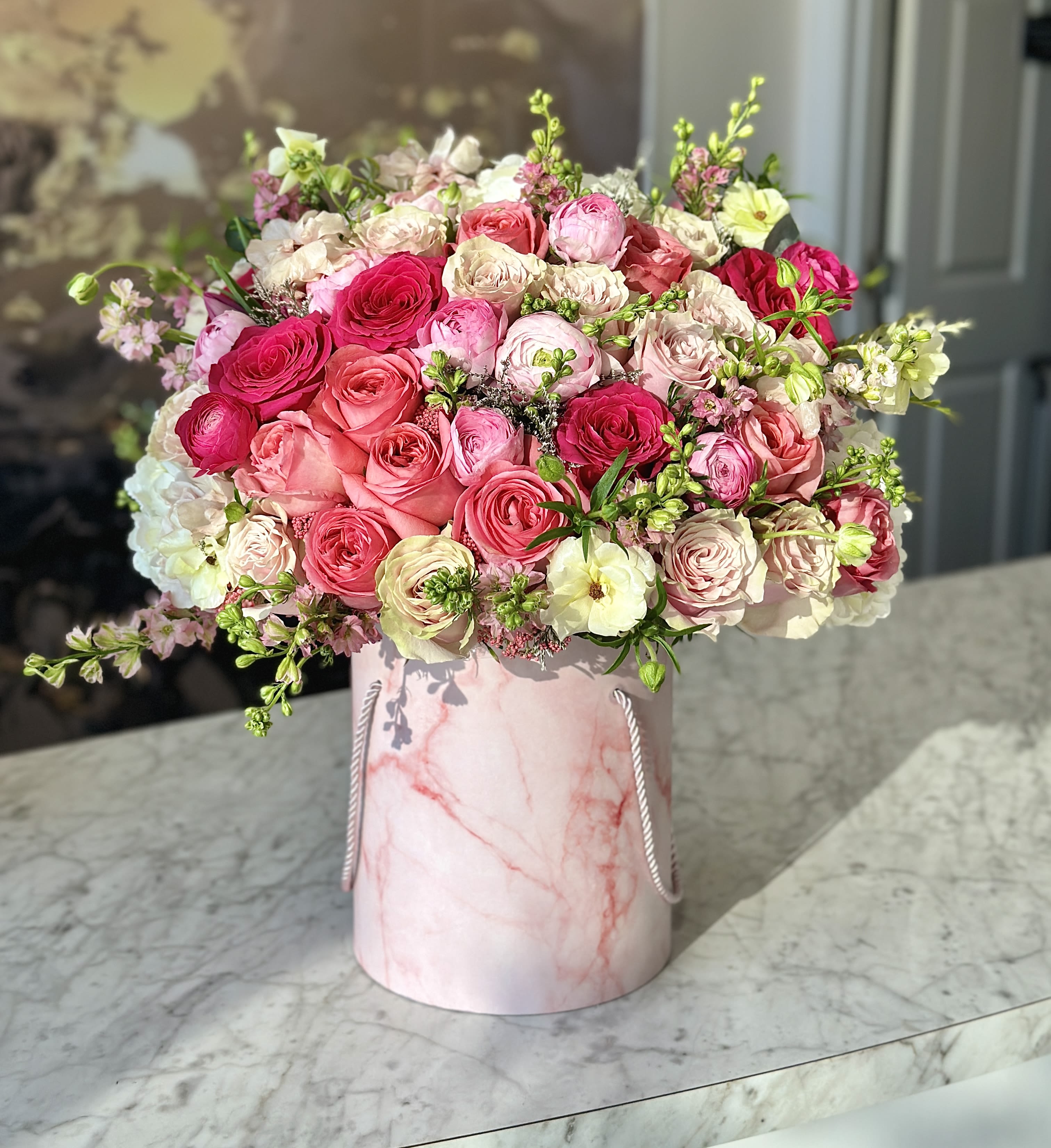 Pink and cream rose bouquet in a marble-patterned hat box