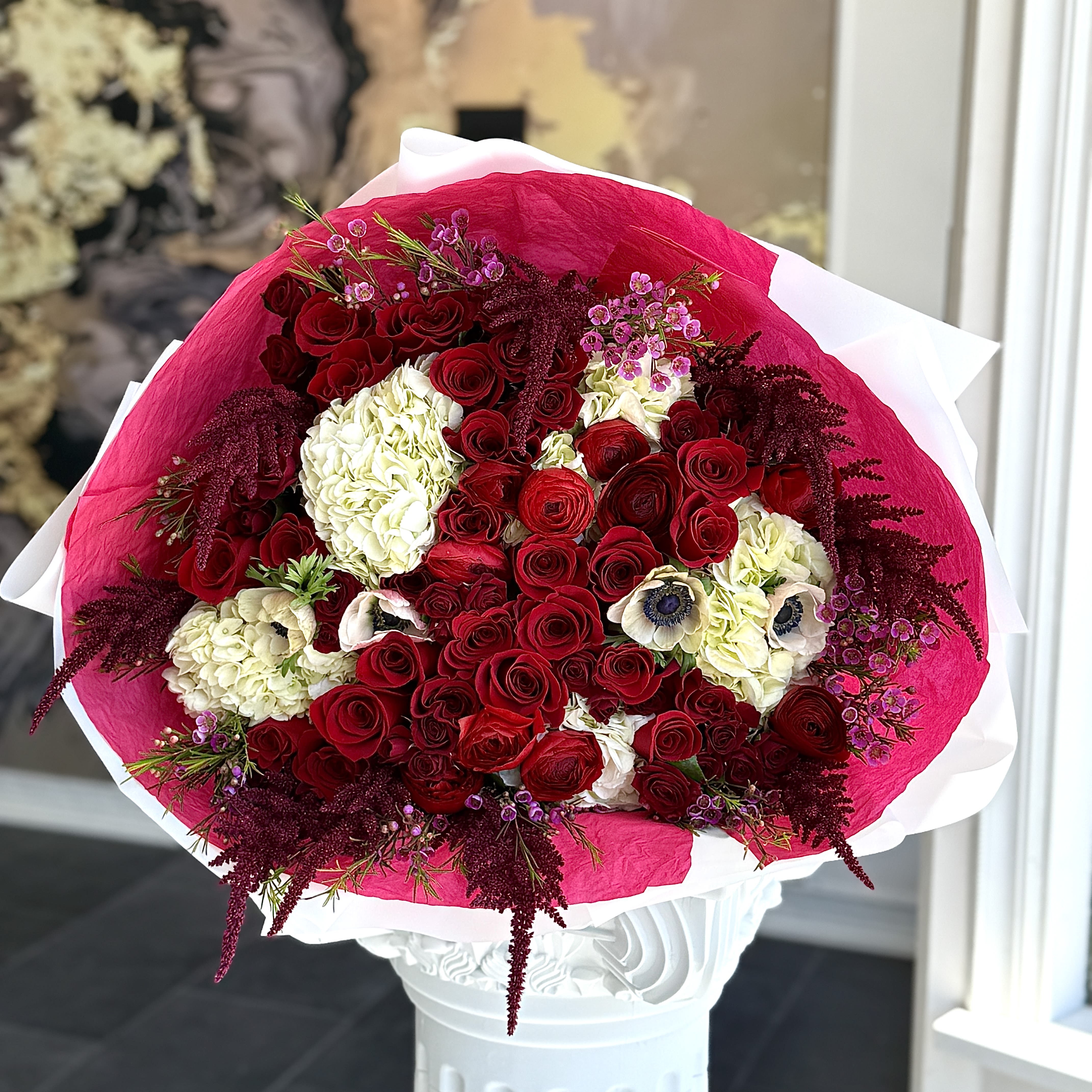 Bouquet of red roses and white hydrangeas wrapped in pink paper