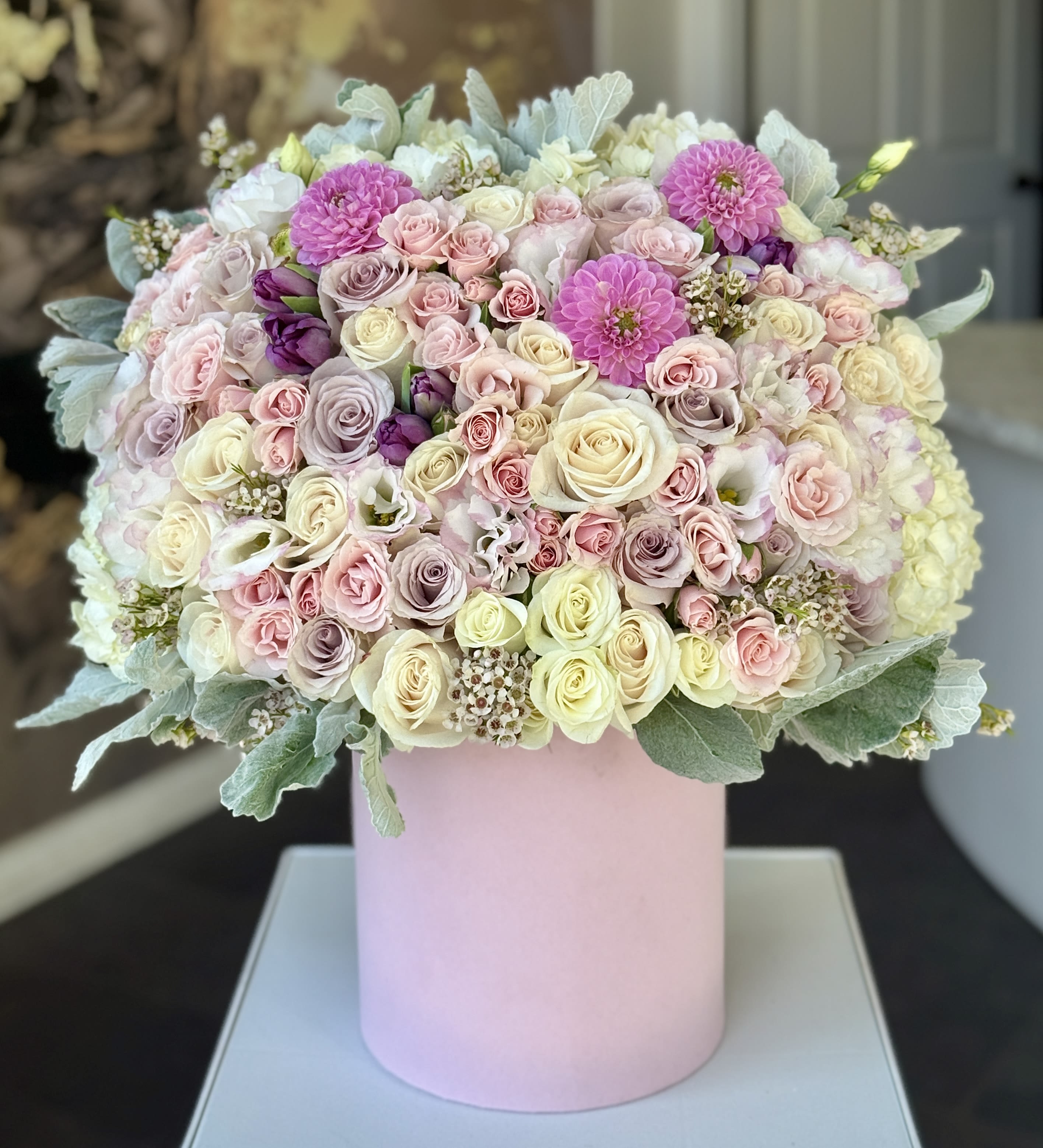 Large pastel bouquet of roses and pink blooms in a pink cylinder box