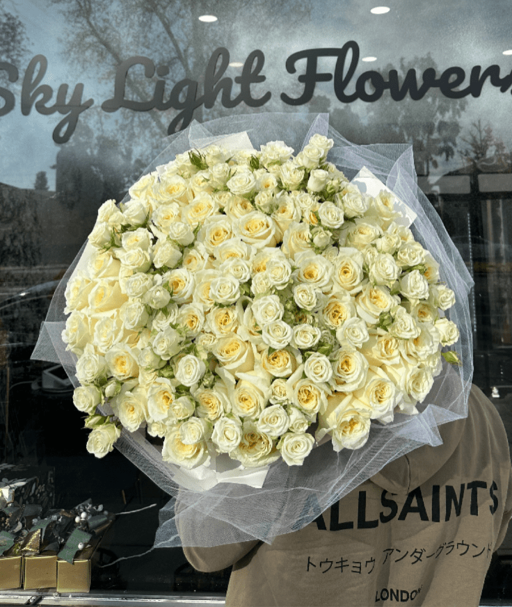 Large bouquet of cream and pale yellow roses wrapped in white tulle