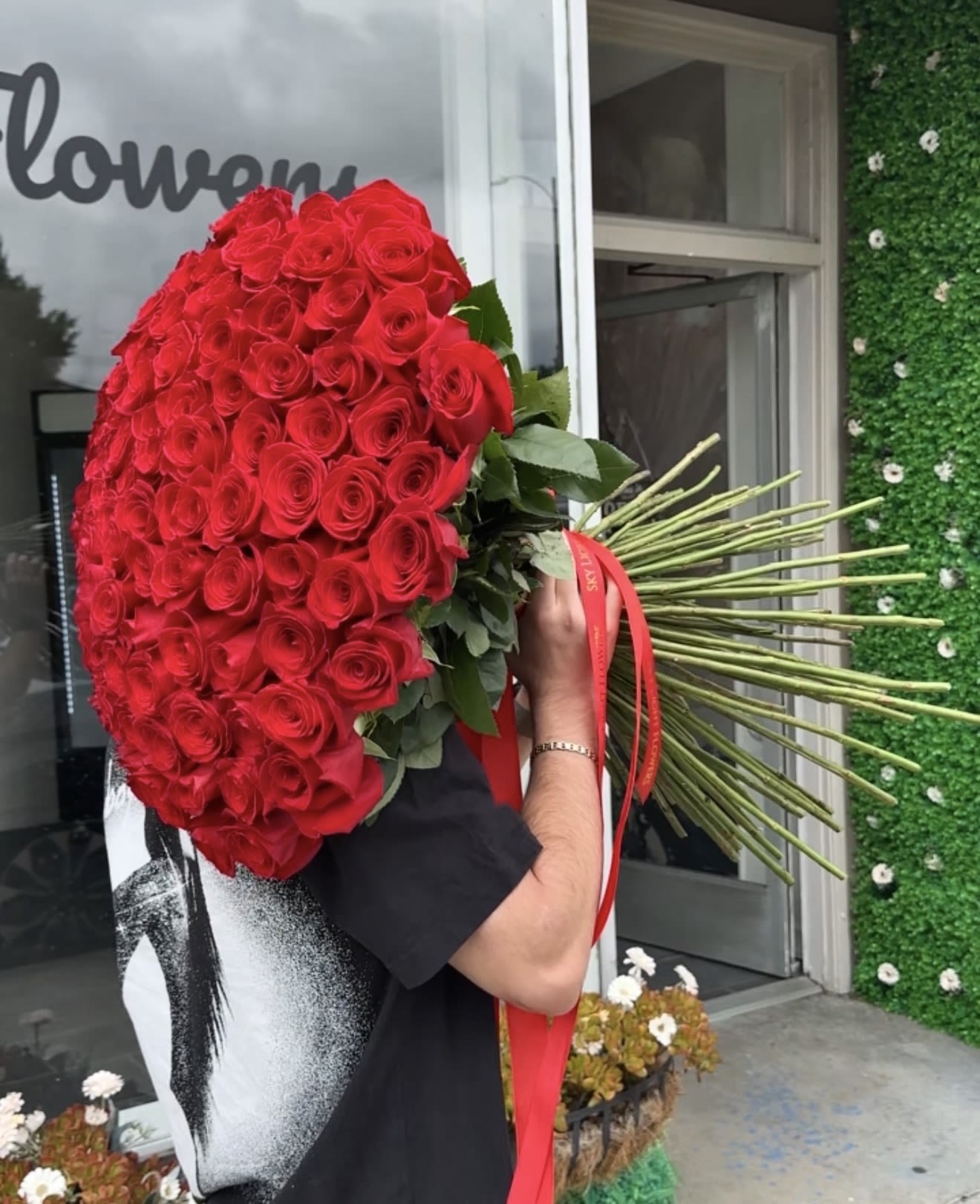 Large bouquet of red roses with long stems and a red ribbon