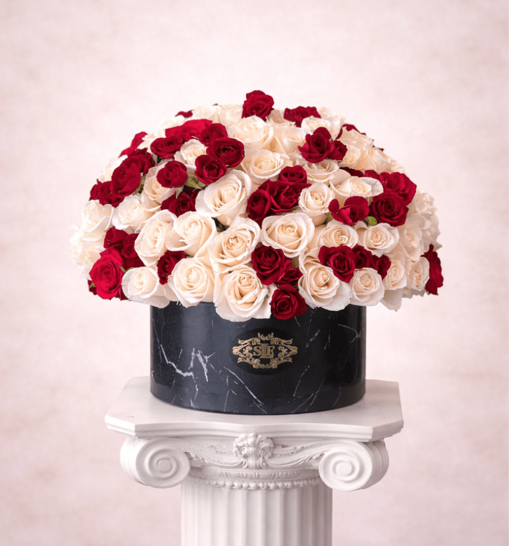 Red and white roses arranged in a black round box
