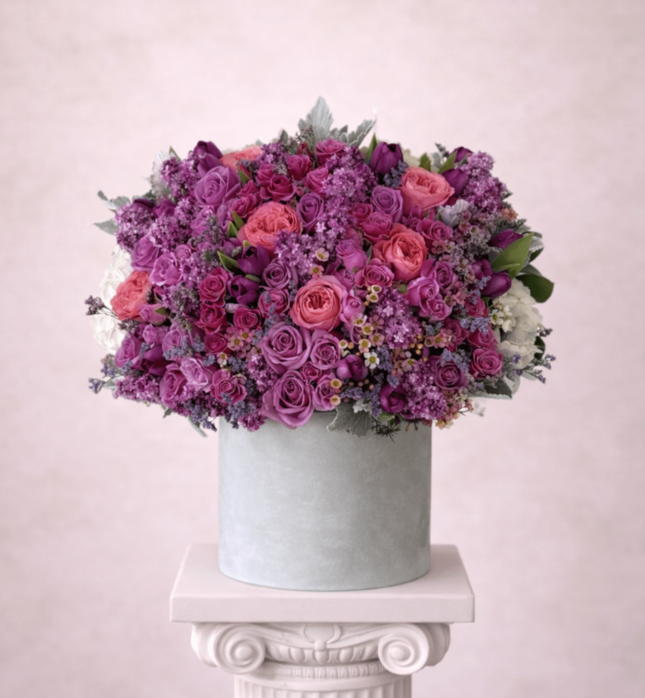 Pink and purple rose arrangement in a gray hat box