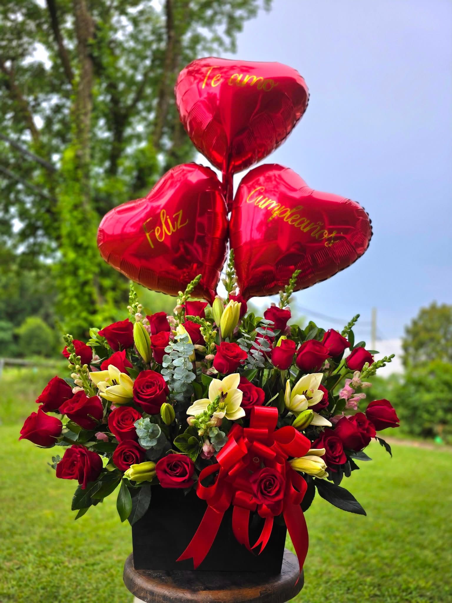 Red rose arrangement with heart balloons and a red ribbon bow