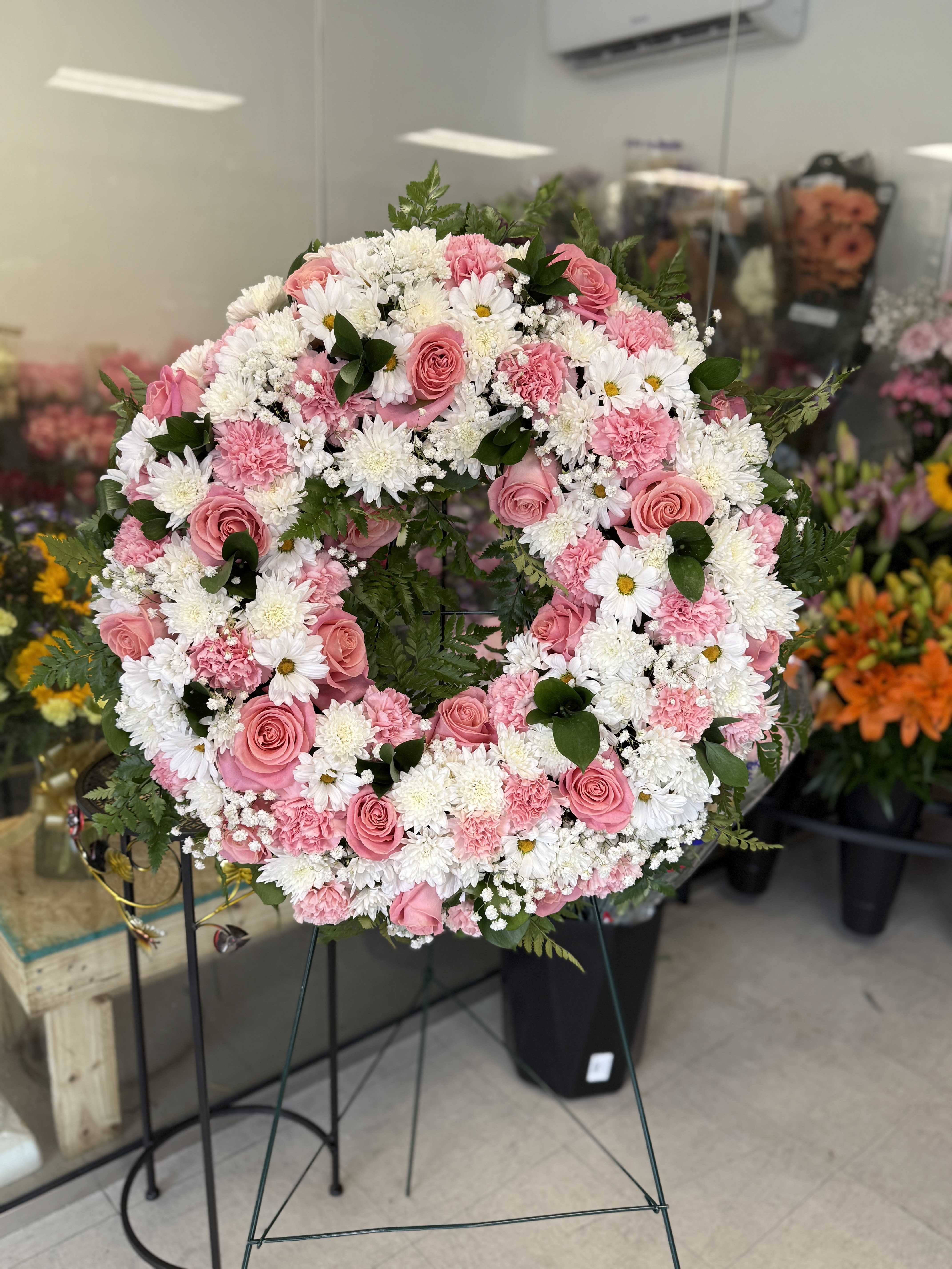 Pink and white floral wreath on a stand