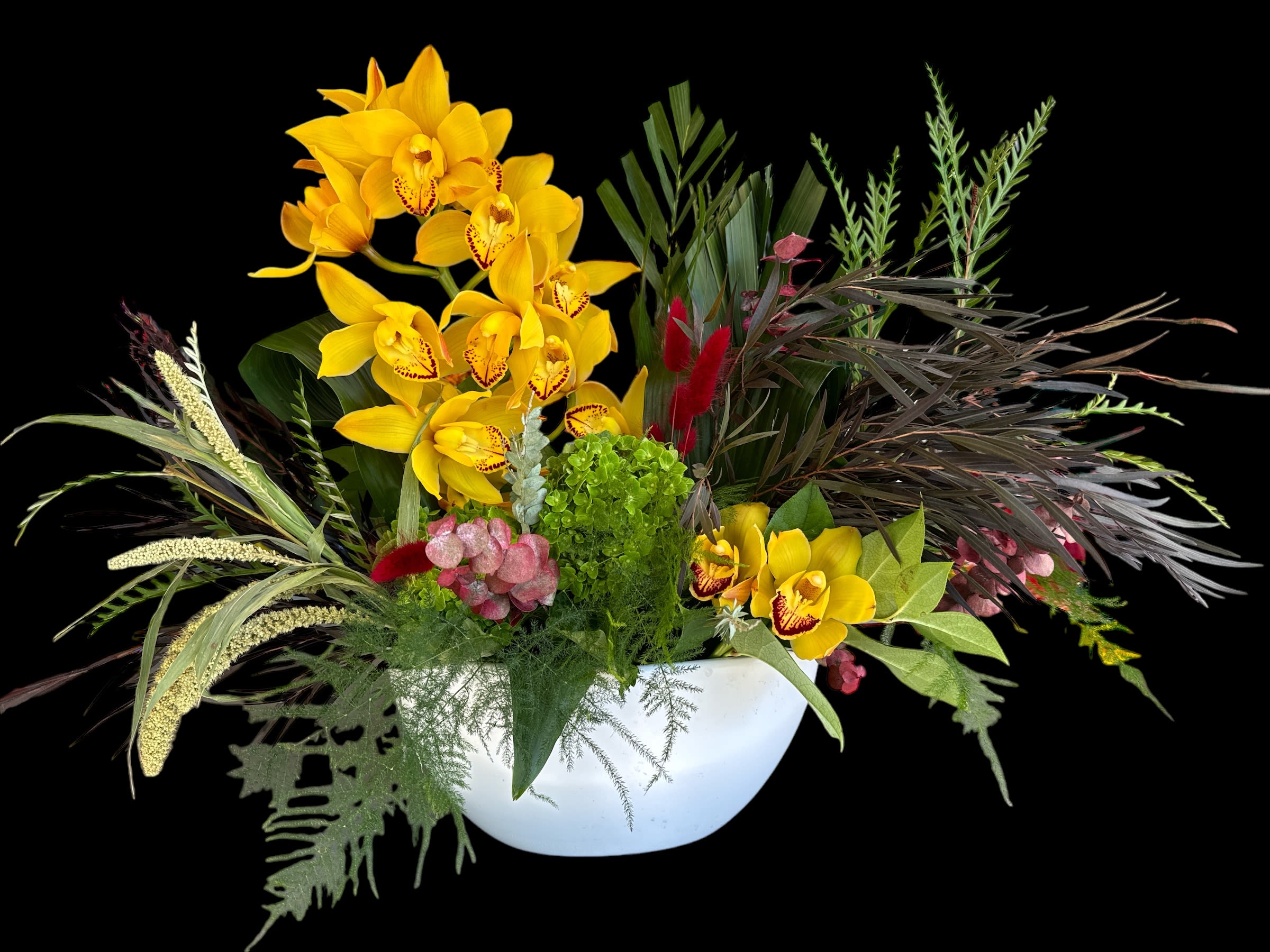 Yellow orchids in a white bowl with mixed tropical foliage