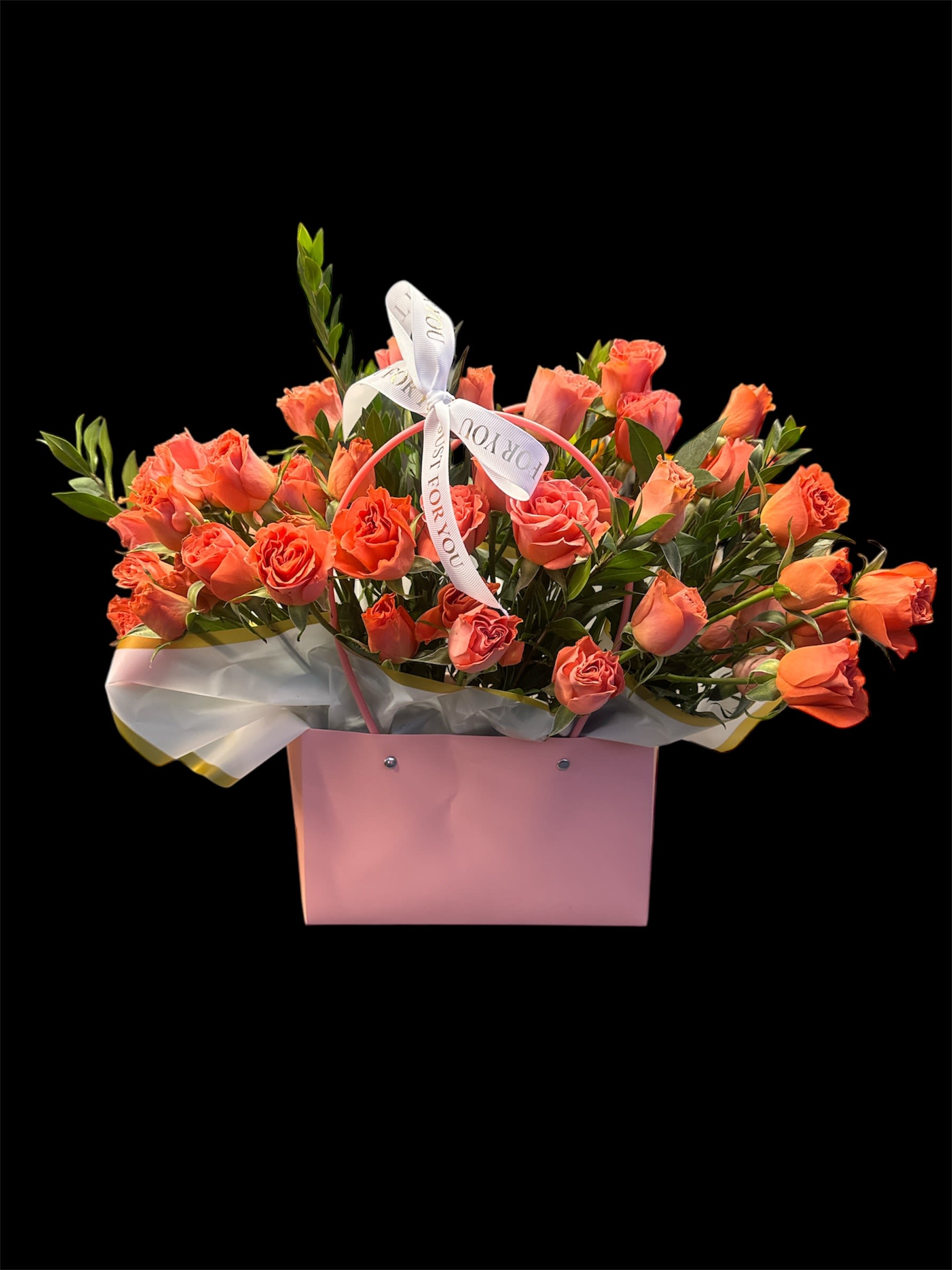Coral roses arranged in a pink gift box with a ribbon bow