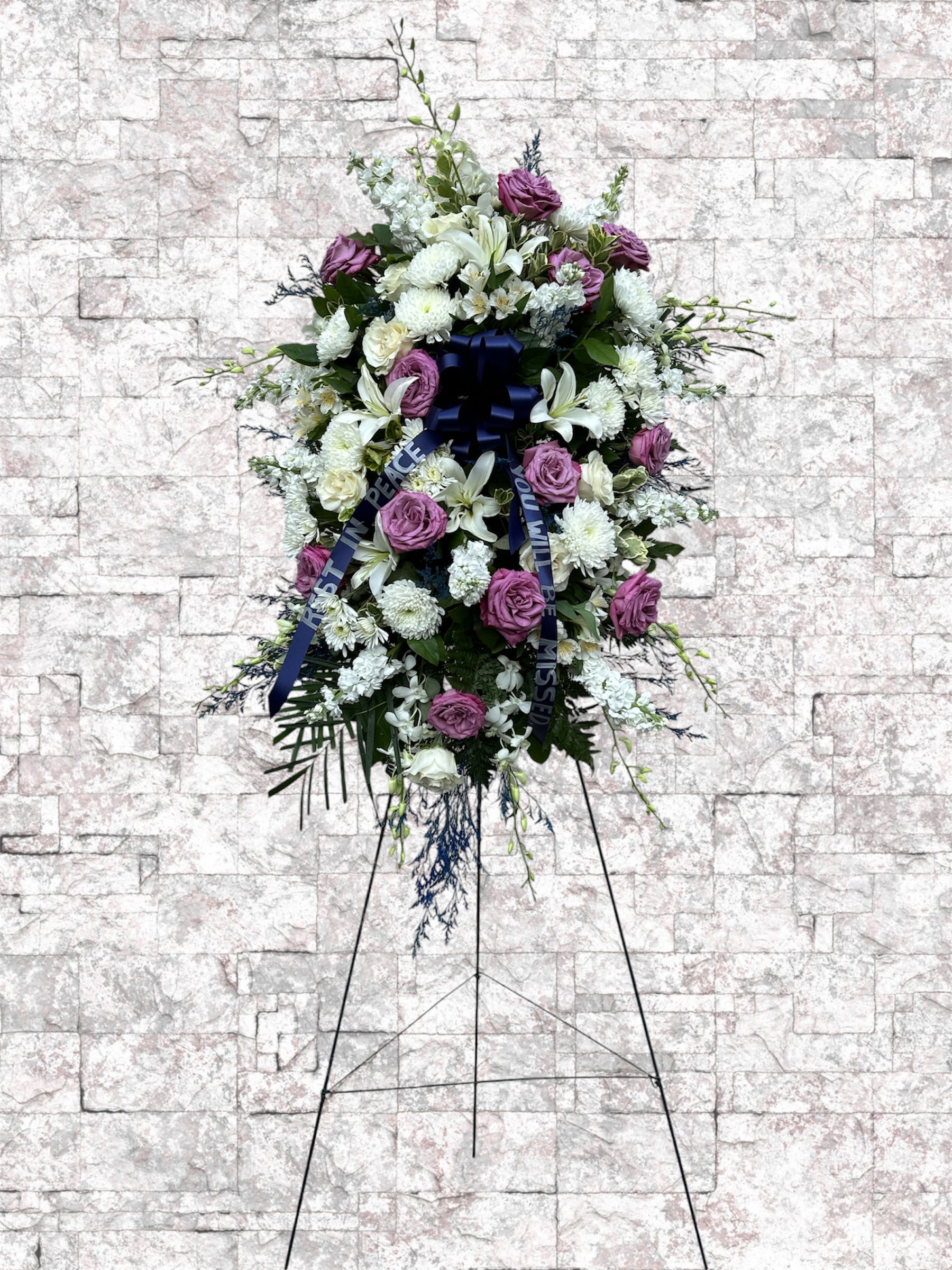 Standing floral wreath with purple and white flowers on an easel