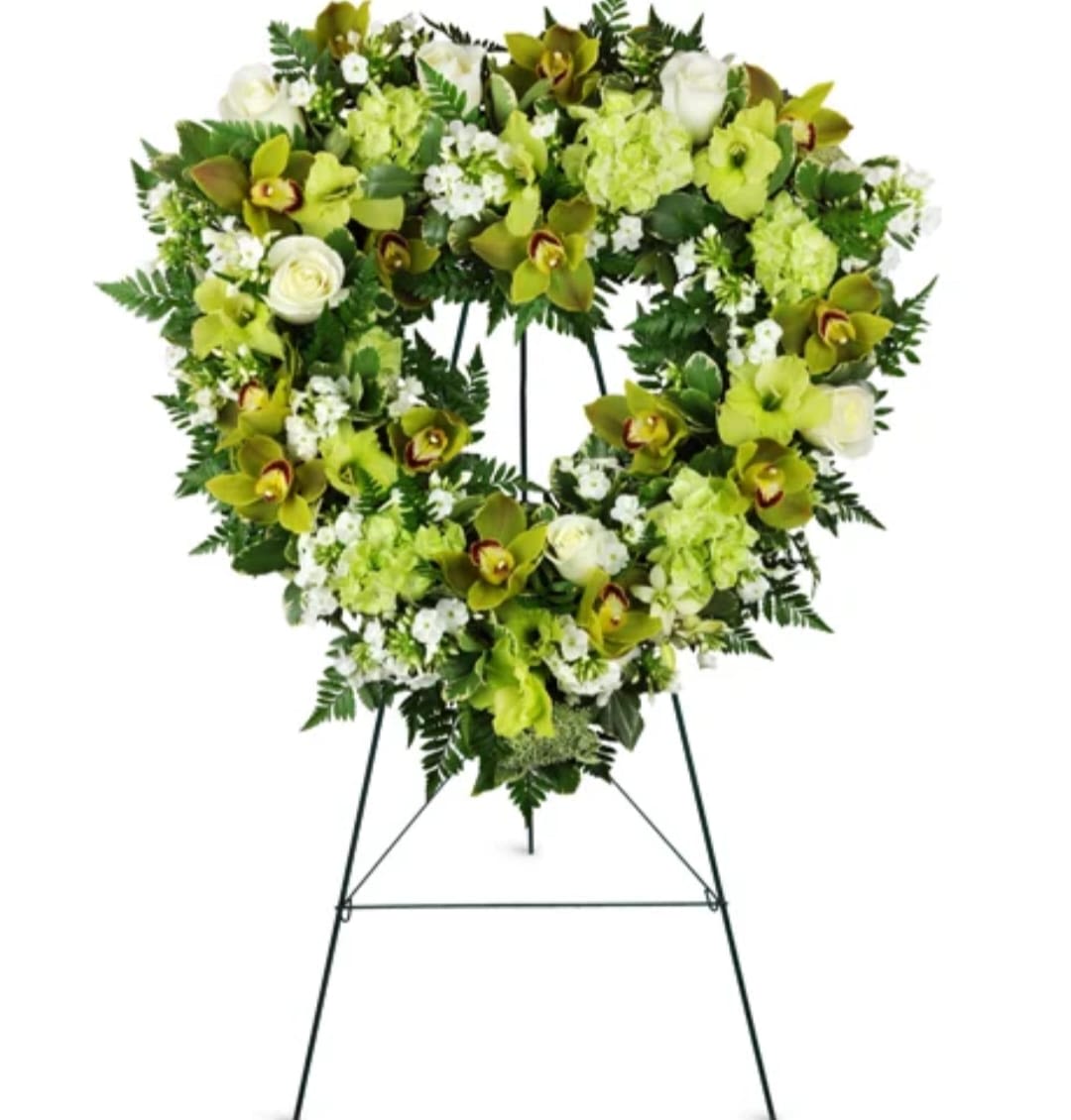 Heart-shaped floral wreath on a standing easel with green and white flowers