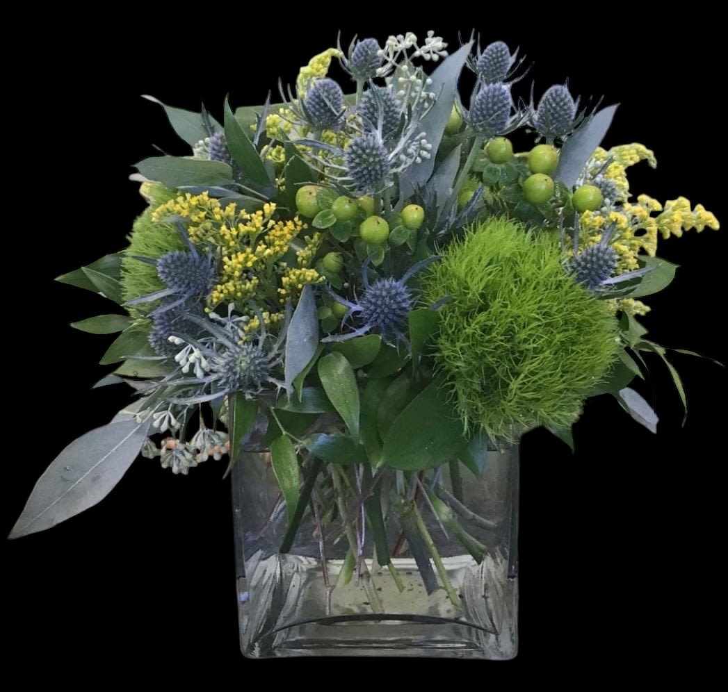 Blue thistle and yellow filler flowers in a clear square vase